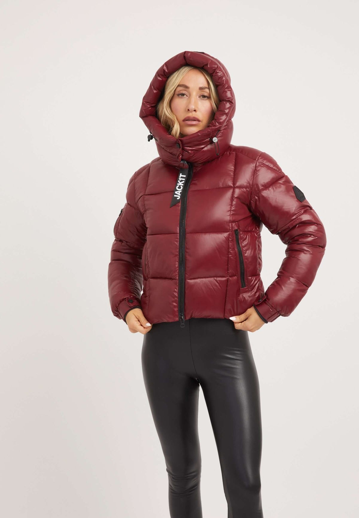 Woman wearing a dark cranberry EZ Box Crop Jacket, a stylish short puffer jacket women, with a hood and sleek design.