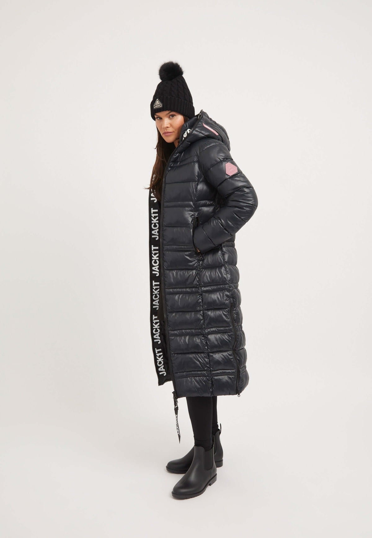 Model wearing R4D Extra Long Puffer Coat in black, featuring a hood, reflective badge, and elasticated cuffs.