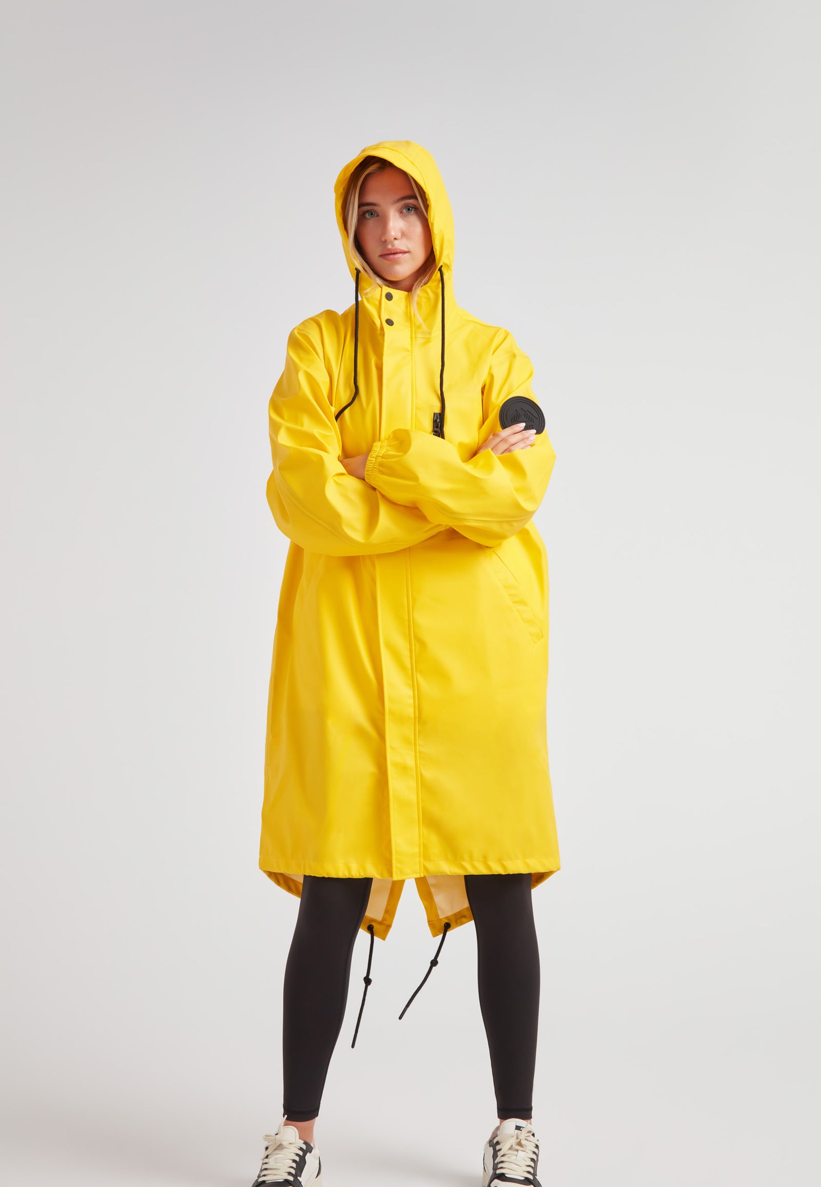 Yellow Elements longline raincoat worn by a model, featuring a hood and relaxed fit for stylish rain protection.