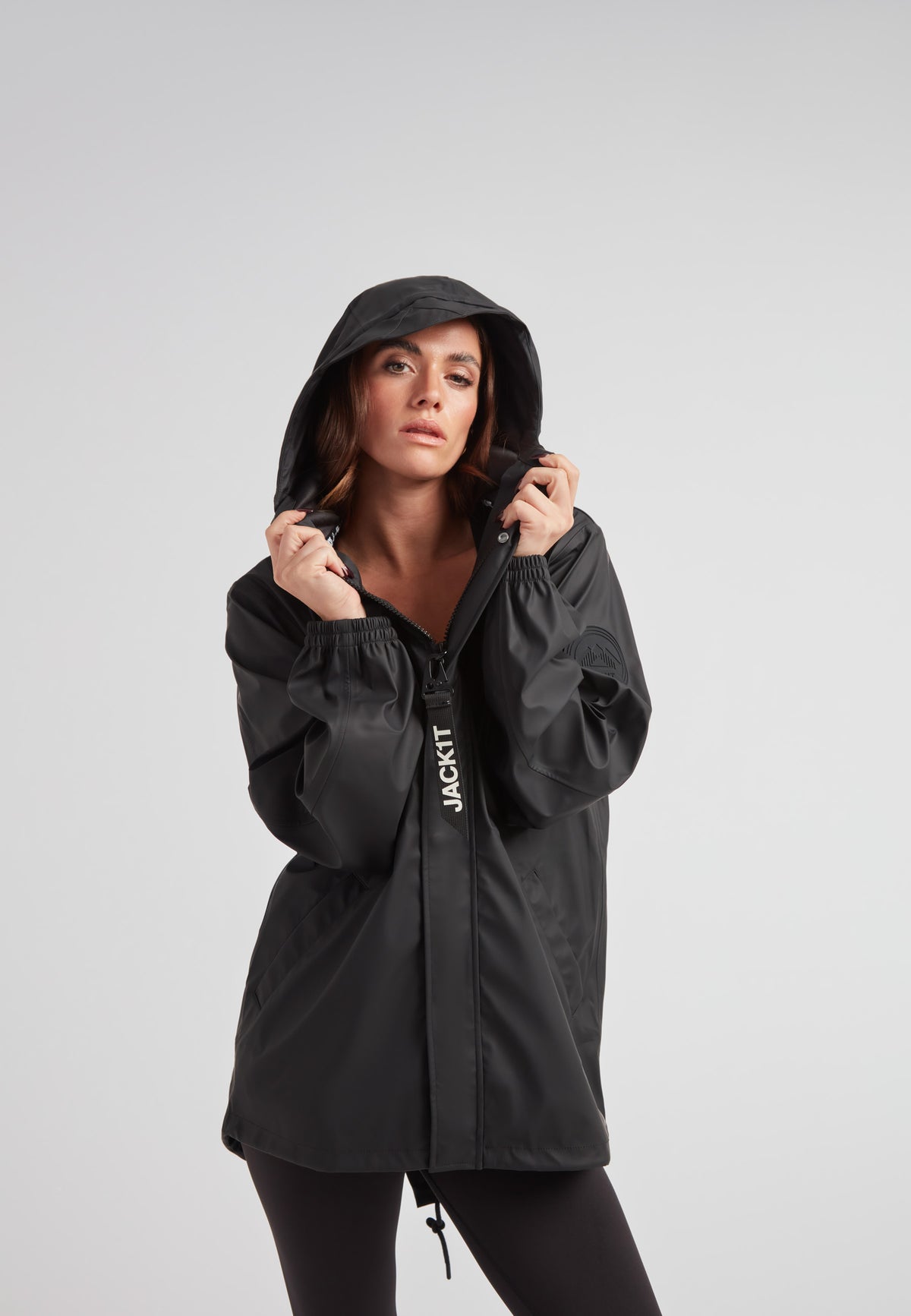 Model wearing the ELEMENTS Raincoat 2.0 Black by JACK1T, showcasing its lightweight design and hood.