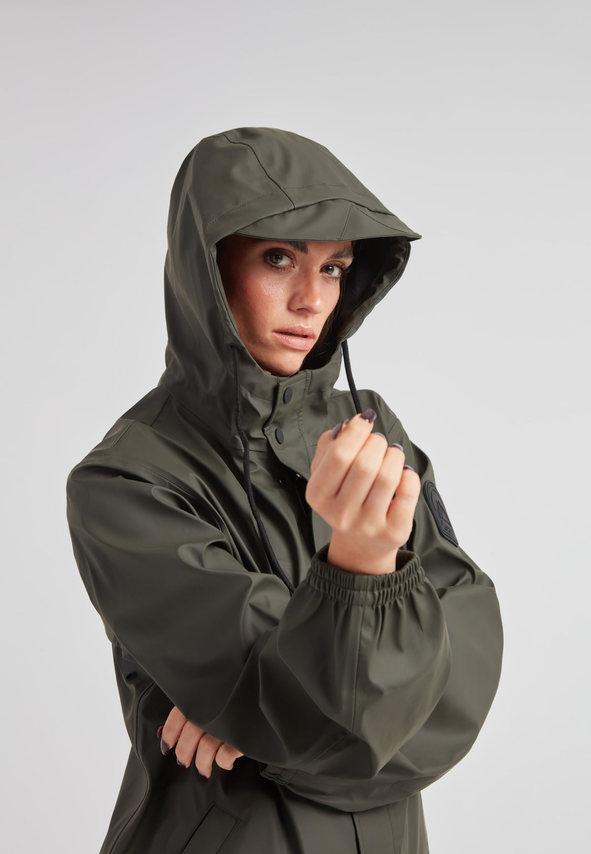 Model wearing the ELEMENTS Raincoat 2.0 Khaki with a hood, showcasing its waterproof features and stylish design.