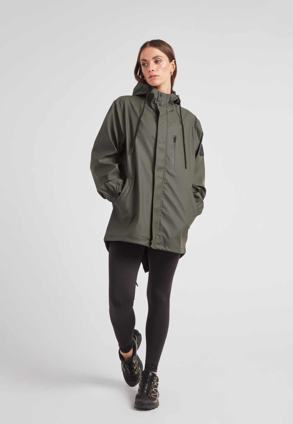 Female model wearing ELEMENTS Raincoat 2.0 Khaki, showcasing its lightweight and versatile design.