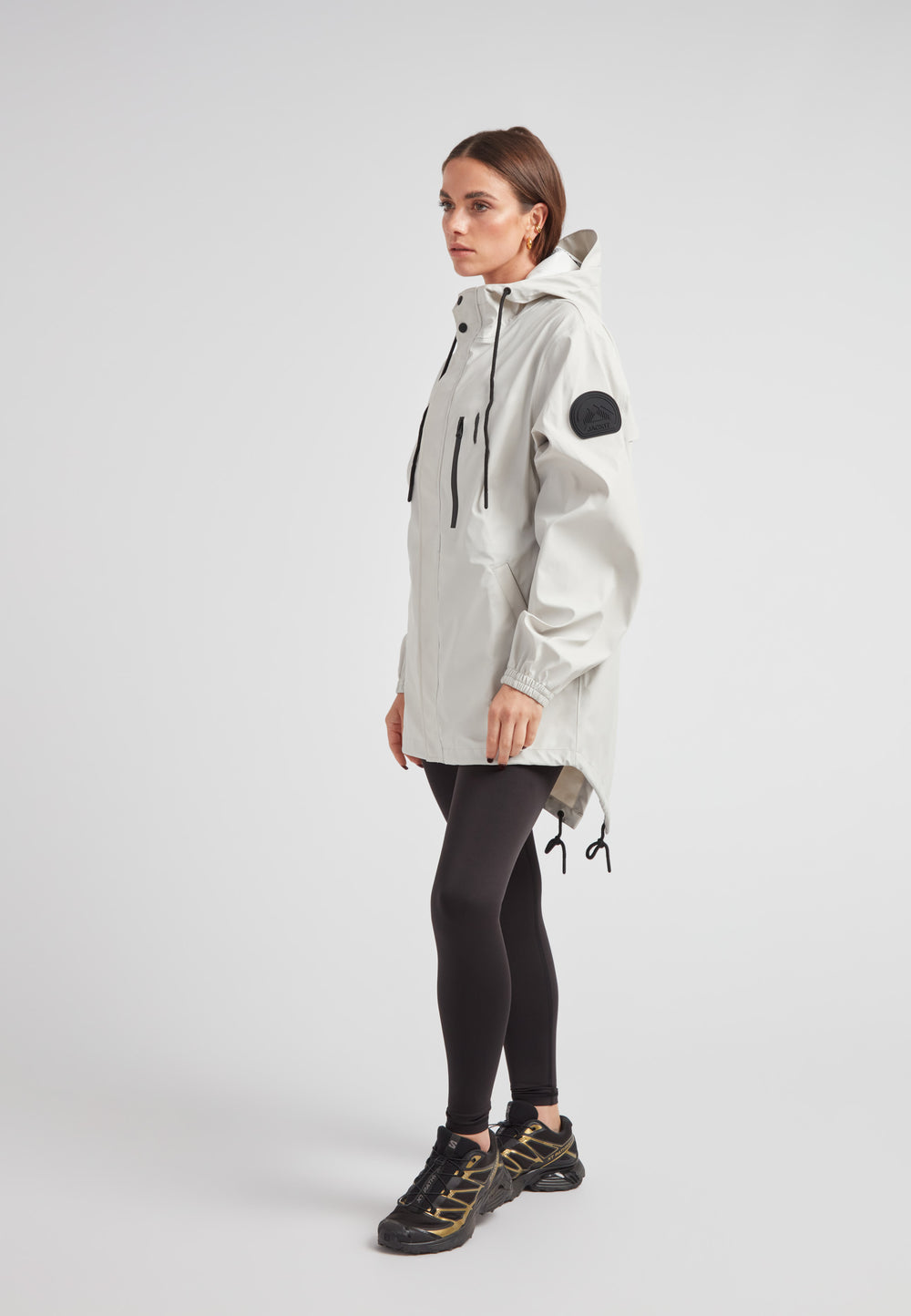 Woman wearing ELEMENTS Raincoat 2.0 Stone, showcasing lightweight weather protection and stylish design.