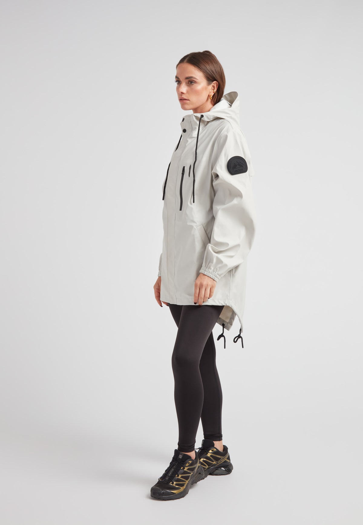 Woman wearing ELEMENTS Raincoat 2.0 Stone, showcasing lightweight weather protection and stylish design.