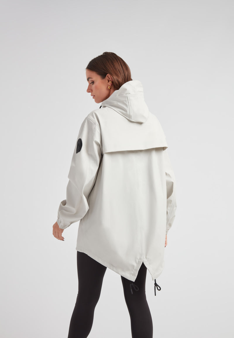 Woman wearing ELEMENTS Raincoat 2.0 Stone, showcasing its stylish back design and lightweight fabric.