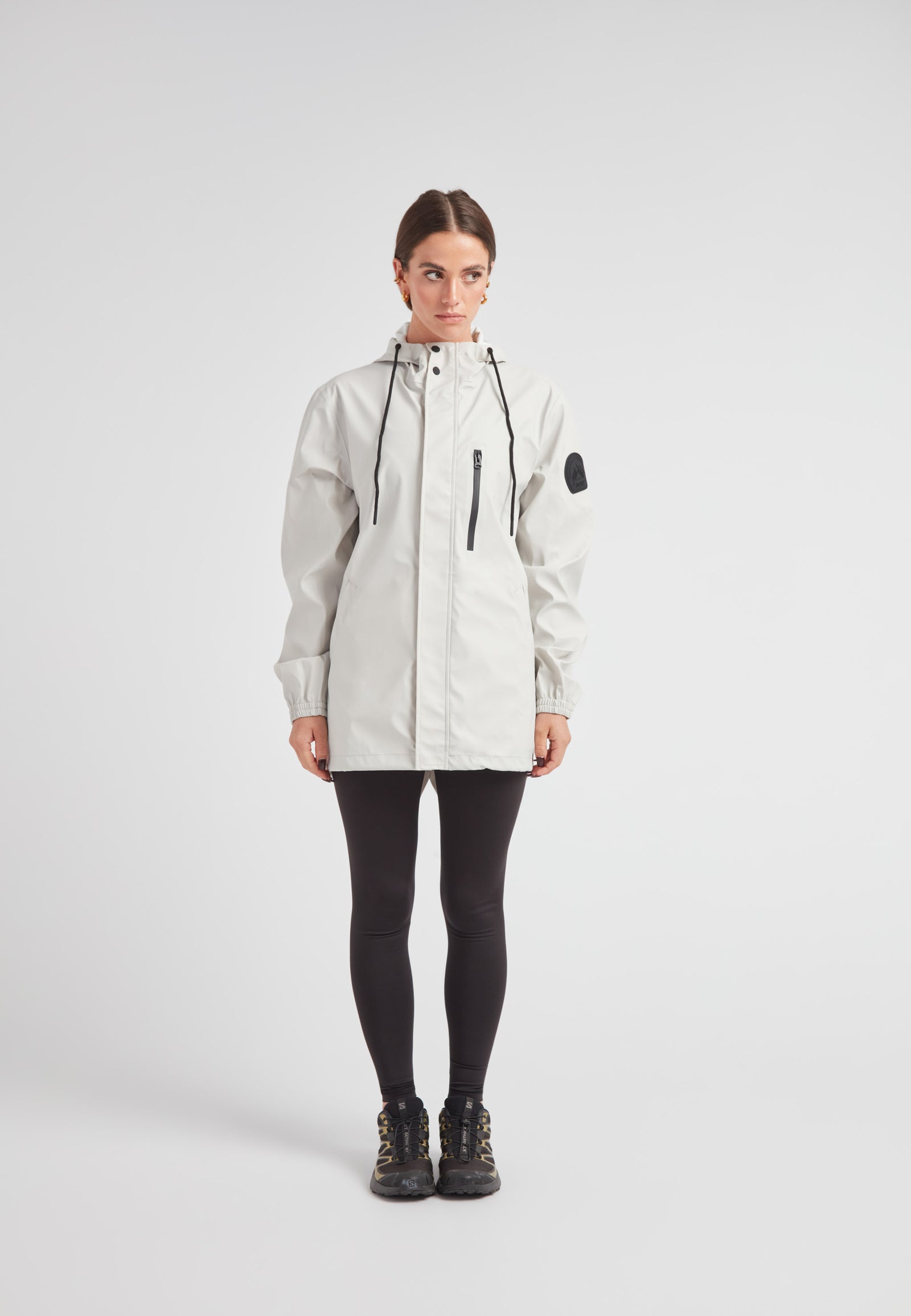 Woman wearing the ELEMENTS Raincoat 2.0 Stone, designed for lightweight weather protection and comfort.