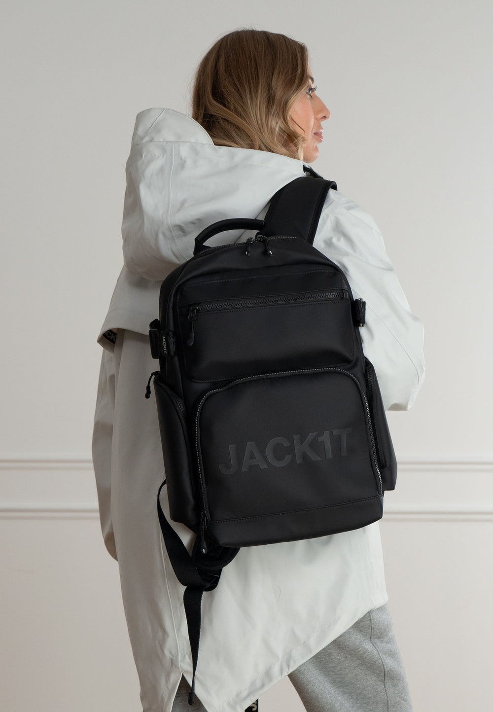 JACK1T's black water resistant backpack worn by a woman in a stylish outfit, showcasing modern design and functionality.