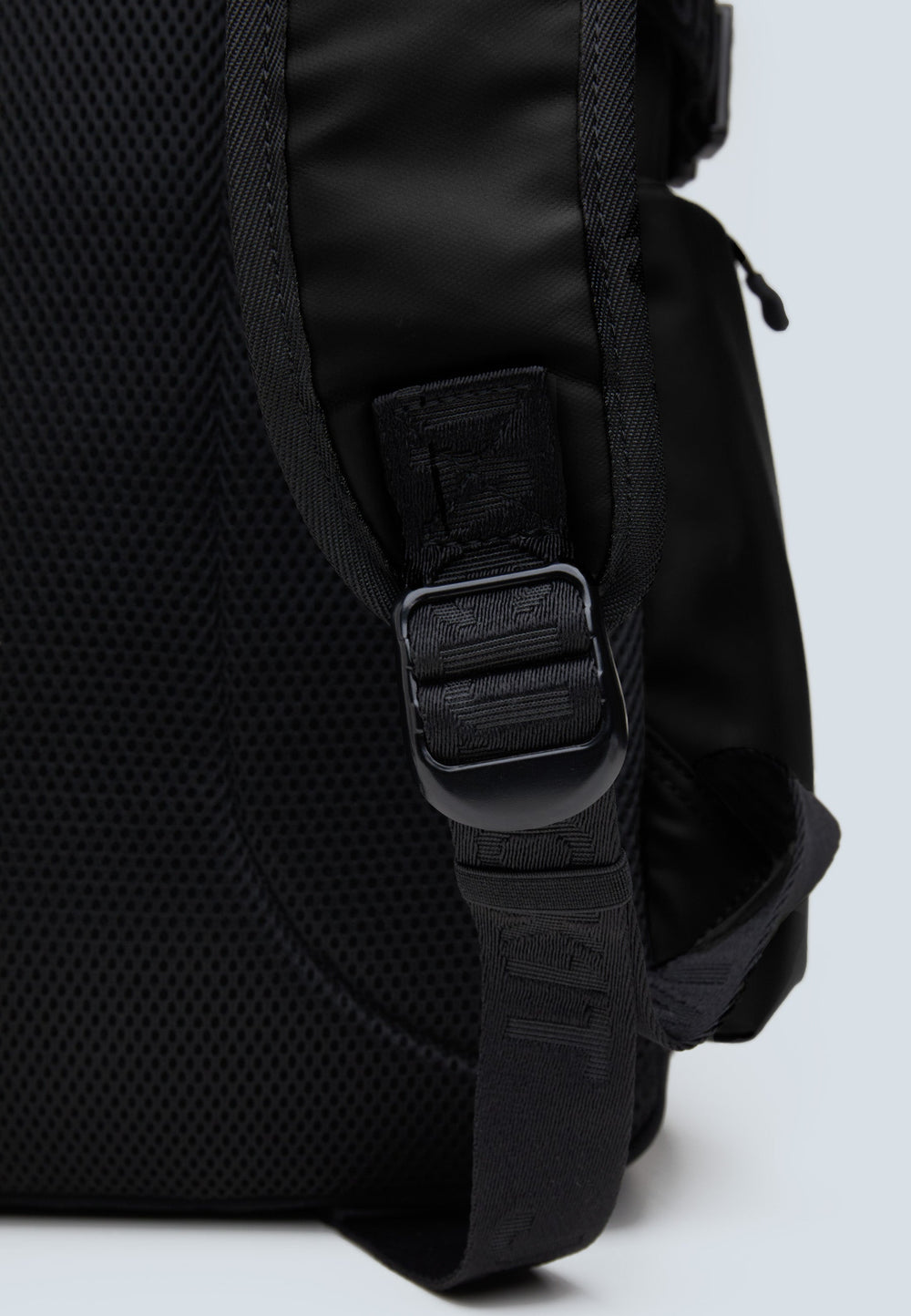 Detail of JACK1T's black water resistant backpack showing the adjustable strap and textured fabric.