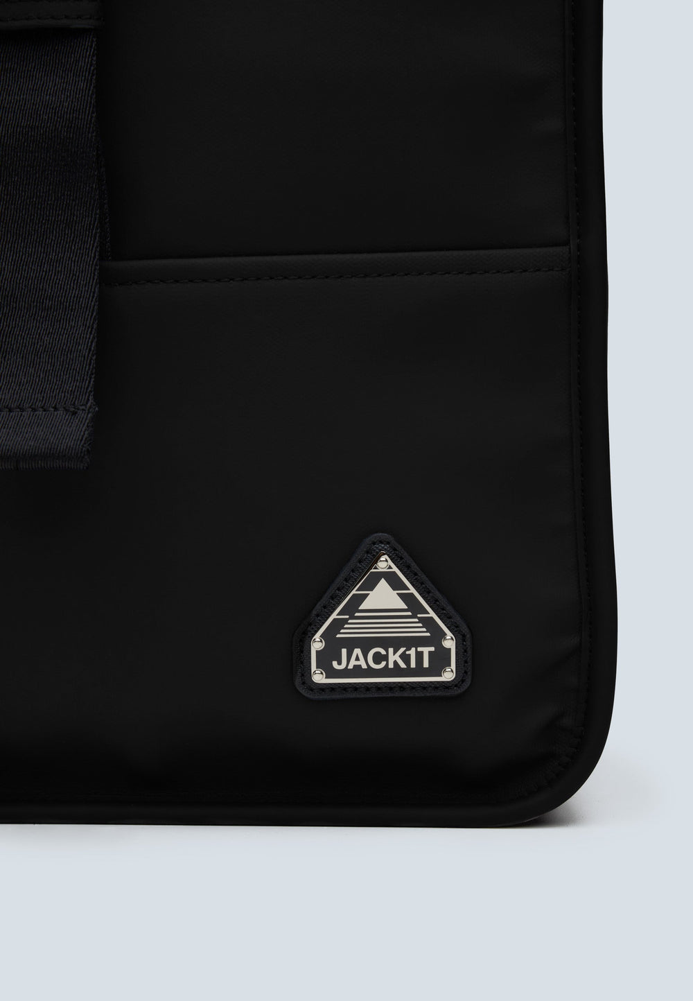 The JACK1T slim messenger laptop bag in black logo close-up on stylish fabric.