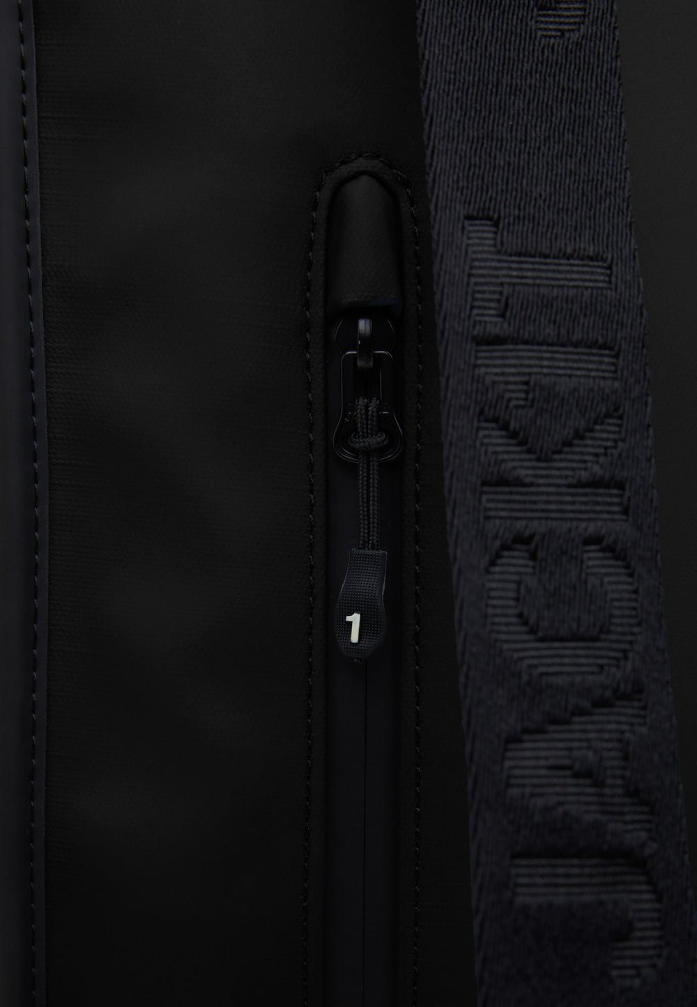 Close-up of The JACK1T slim messenger laptop bag in black showcasing zipper detail and brand logo.