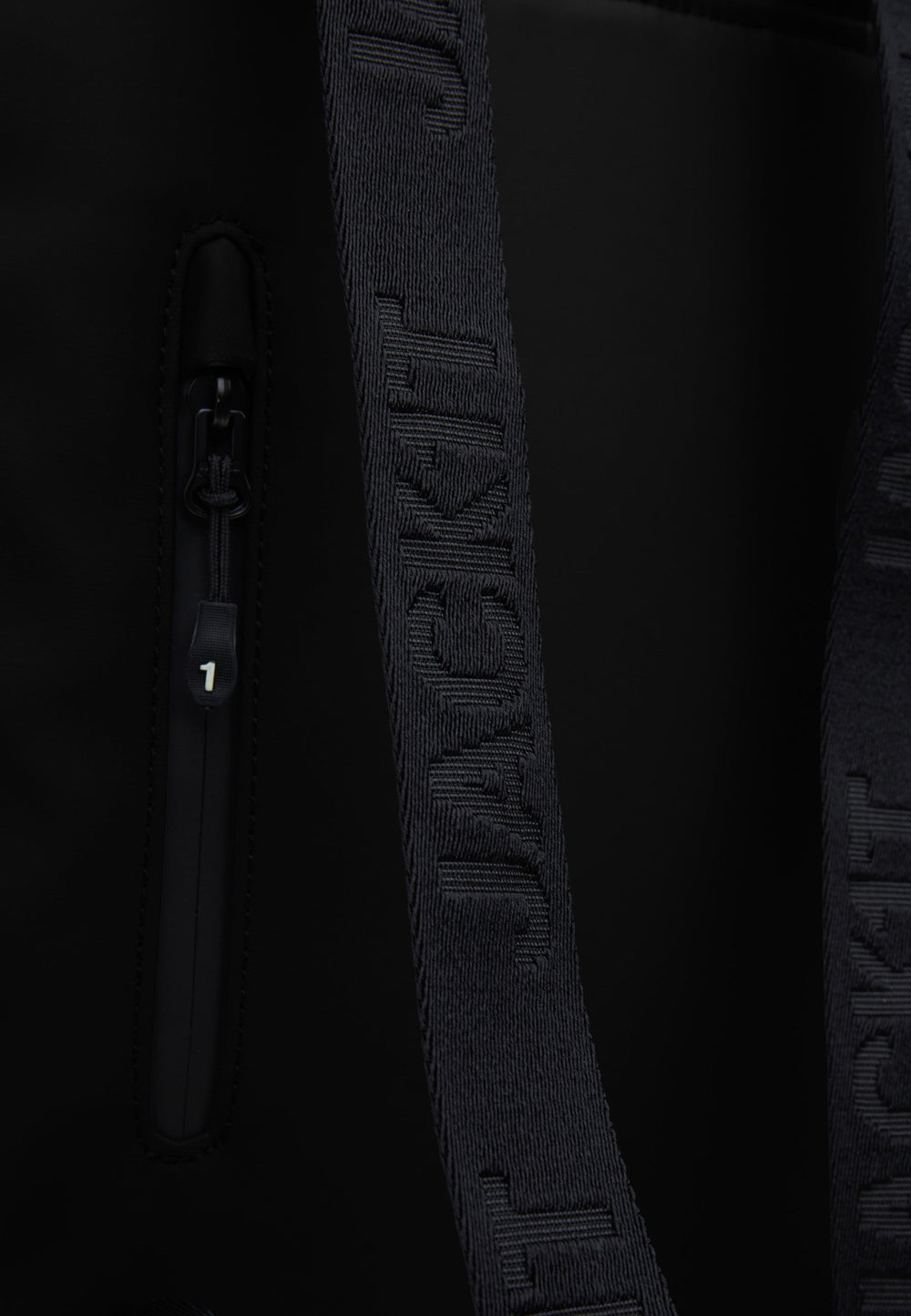 Close-up of The JACK1T slim messenger laptop bag in black showing the strap and zip detail.