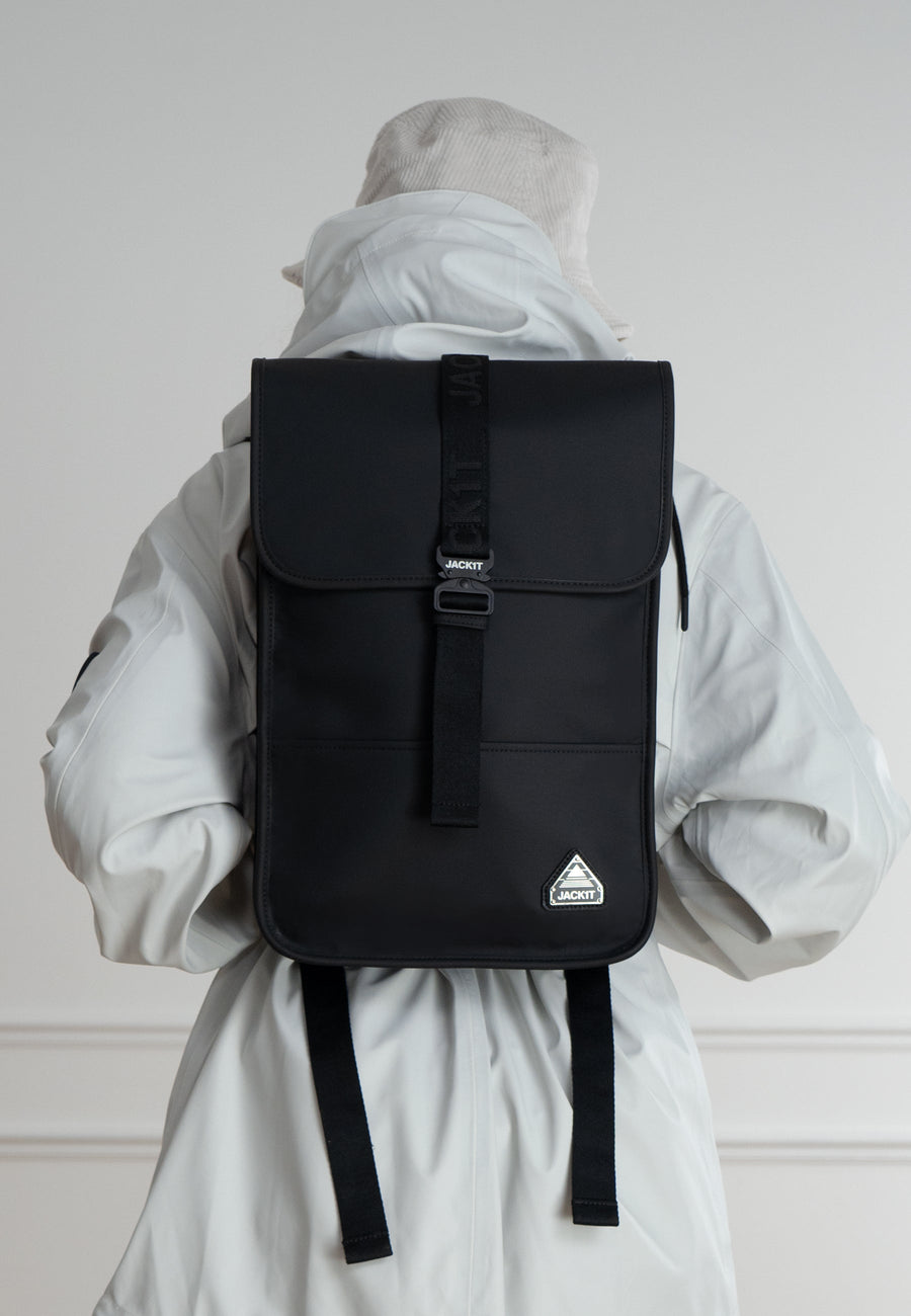The JACK1T slim messenger laptop bag in black worn by a person in a white jacket from behind.