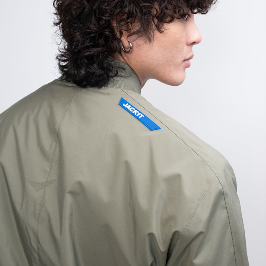 Man wearing Oberon Tech Bomber  Jacket with a 'JACKTT' label on the back against a light gray background 