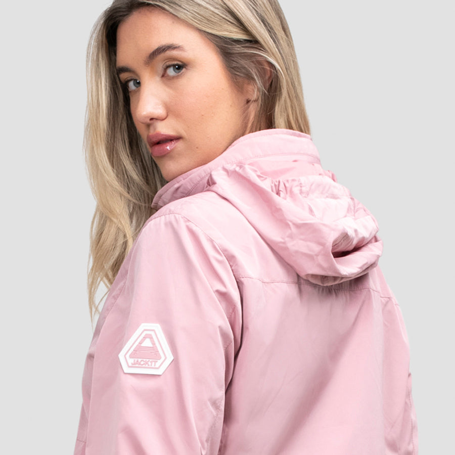 Woman wearing a Atlas Lightweight Windbreaker in pink with JACK1T logo on a light gray background 