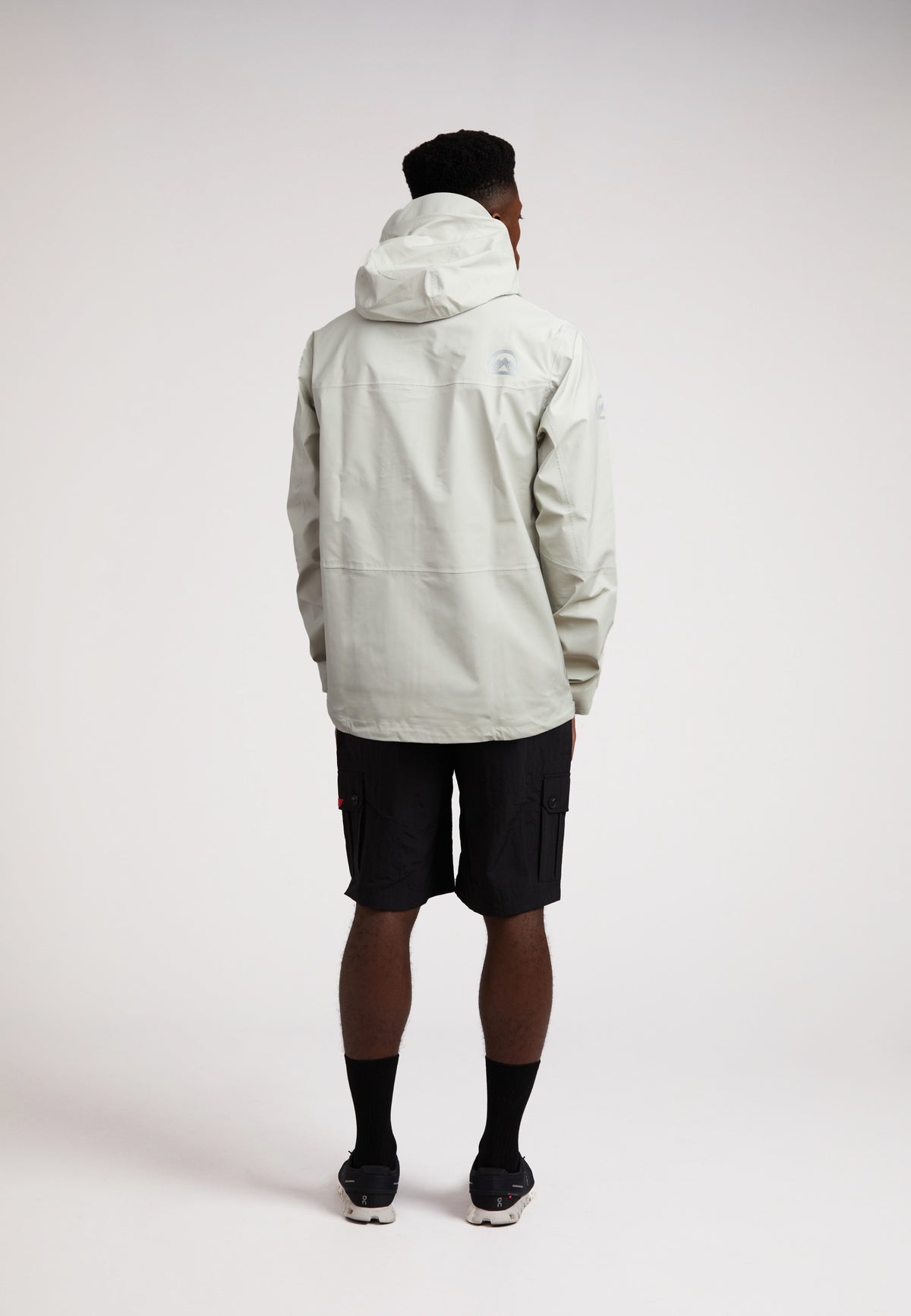 Stone mens lithium waterproof jacket worn by a man from the back, showcasing its design and materials in a neutral setting.