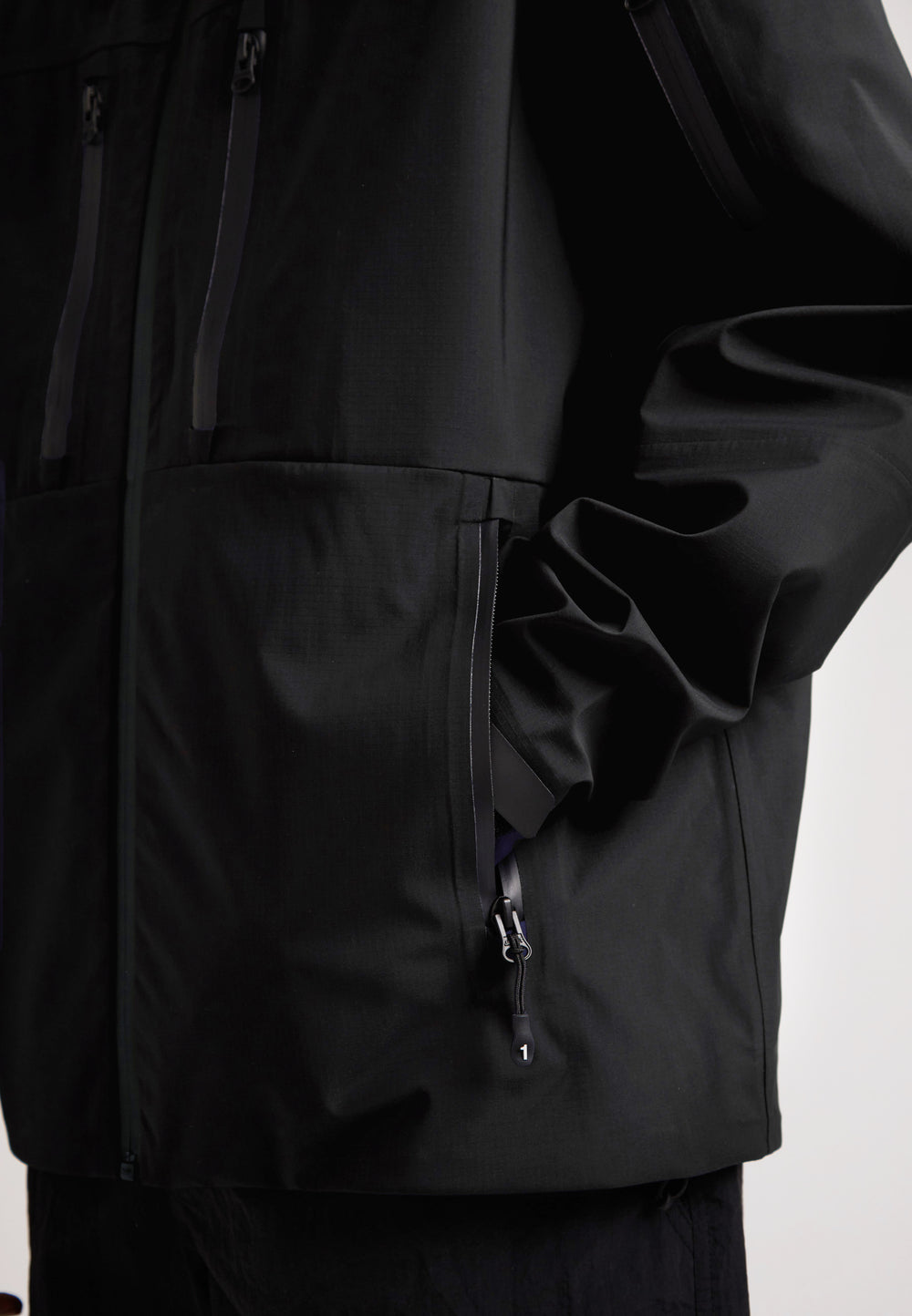 Black mens Lithium waterproof jacket showcasing a close-up of the zippered pockets and durable design.
