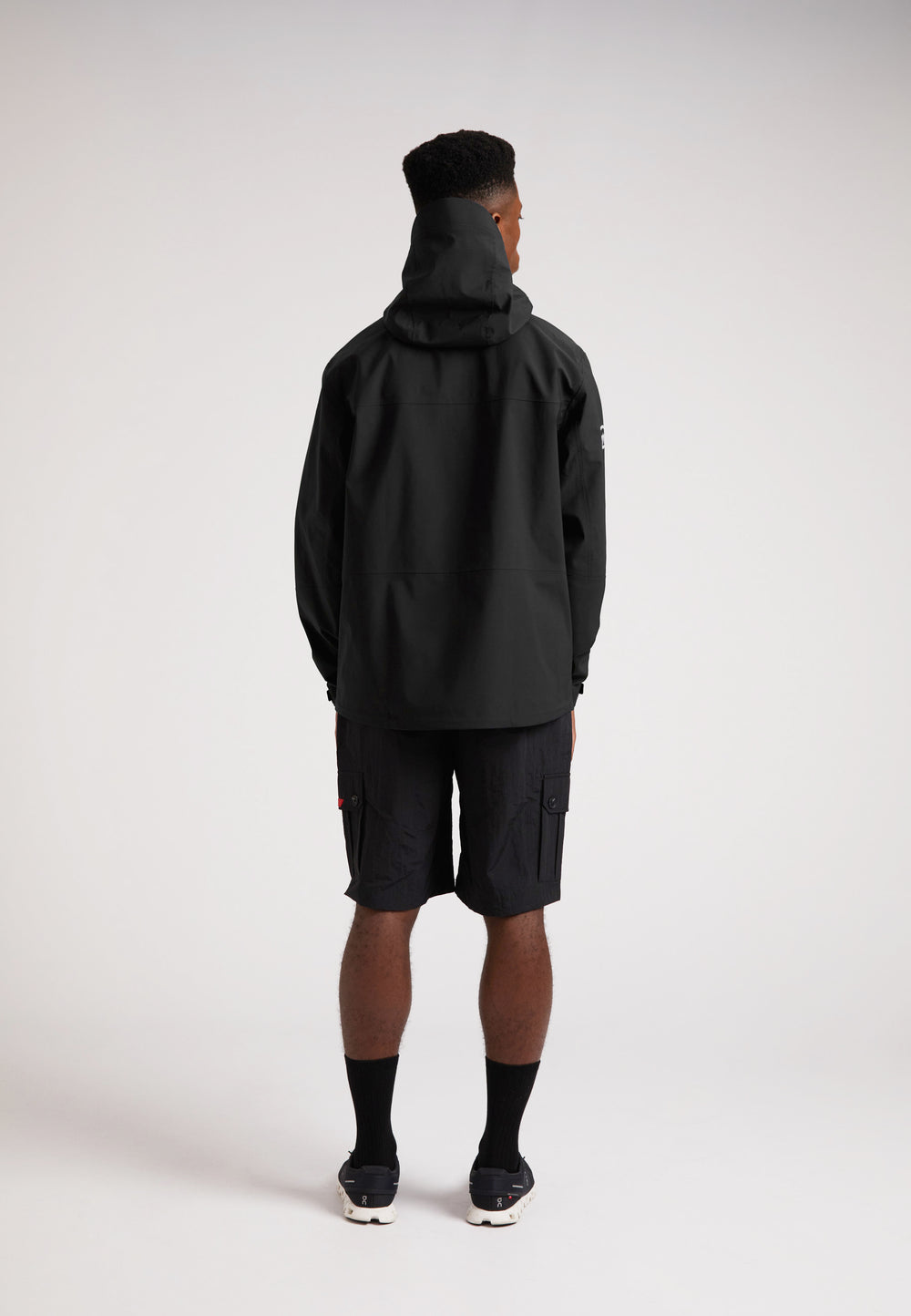 Black mens Lithium waterproof jacket on model from the back, showcasing the hoodie and durable design.