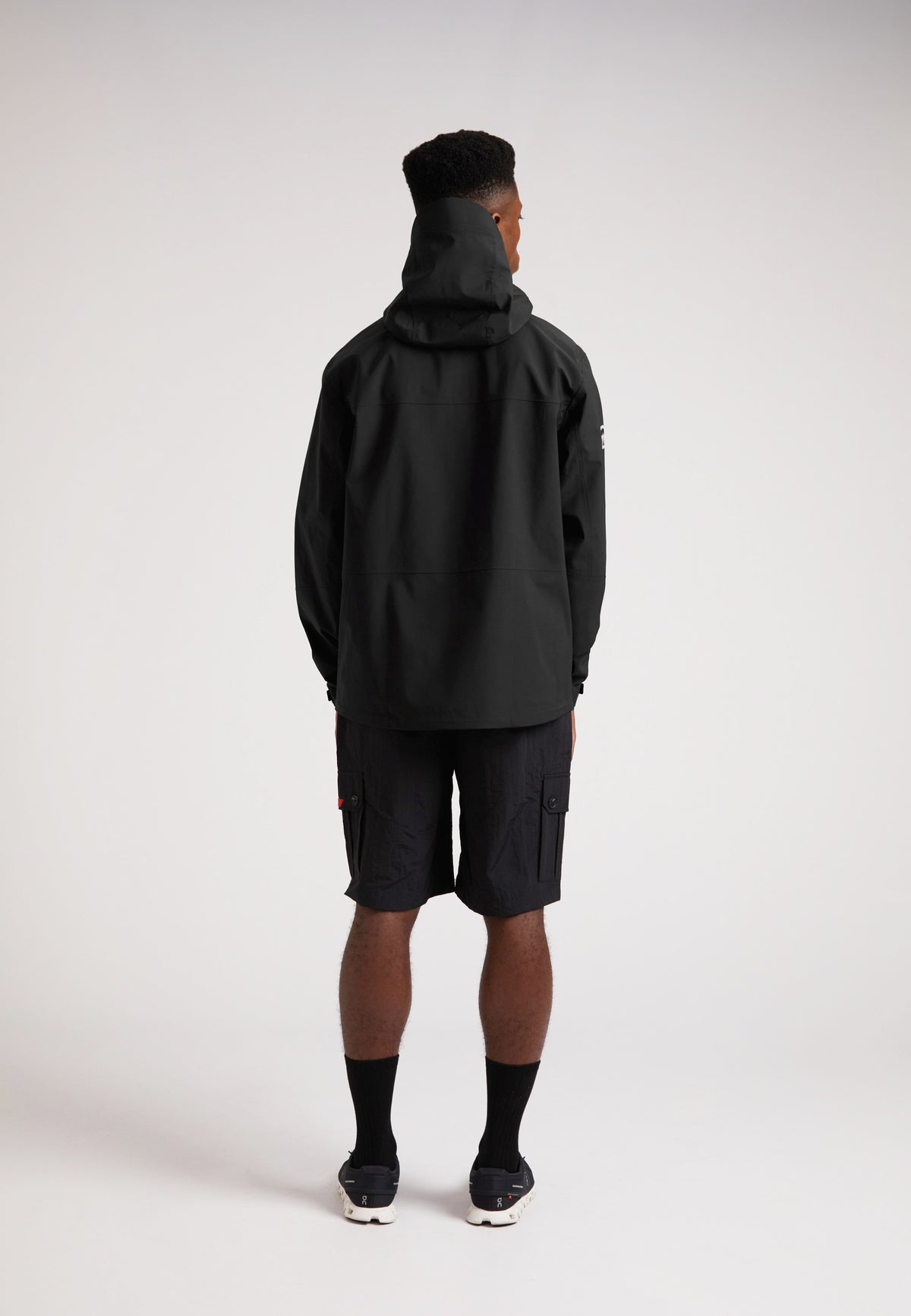 Black mens Lithium waterproof jacket on model from the back, showcasing the hoodie and durable design.