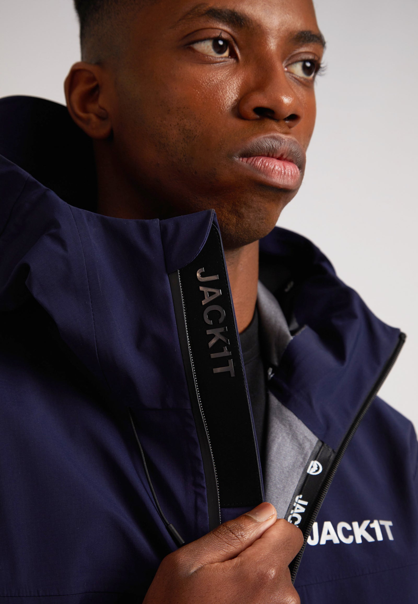 Man wearing a navy lithium waterproof mens jacket with the JACKIT logo visible on the zipper.