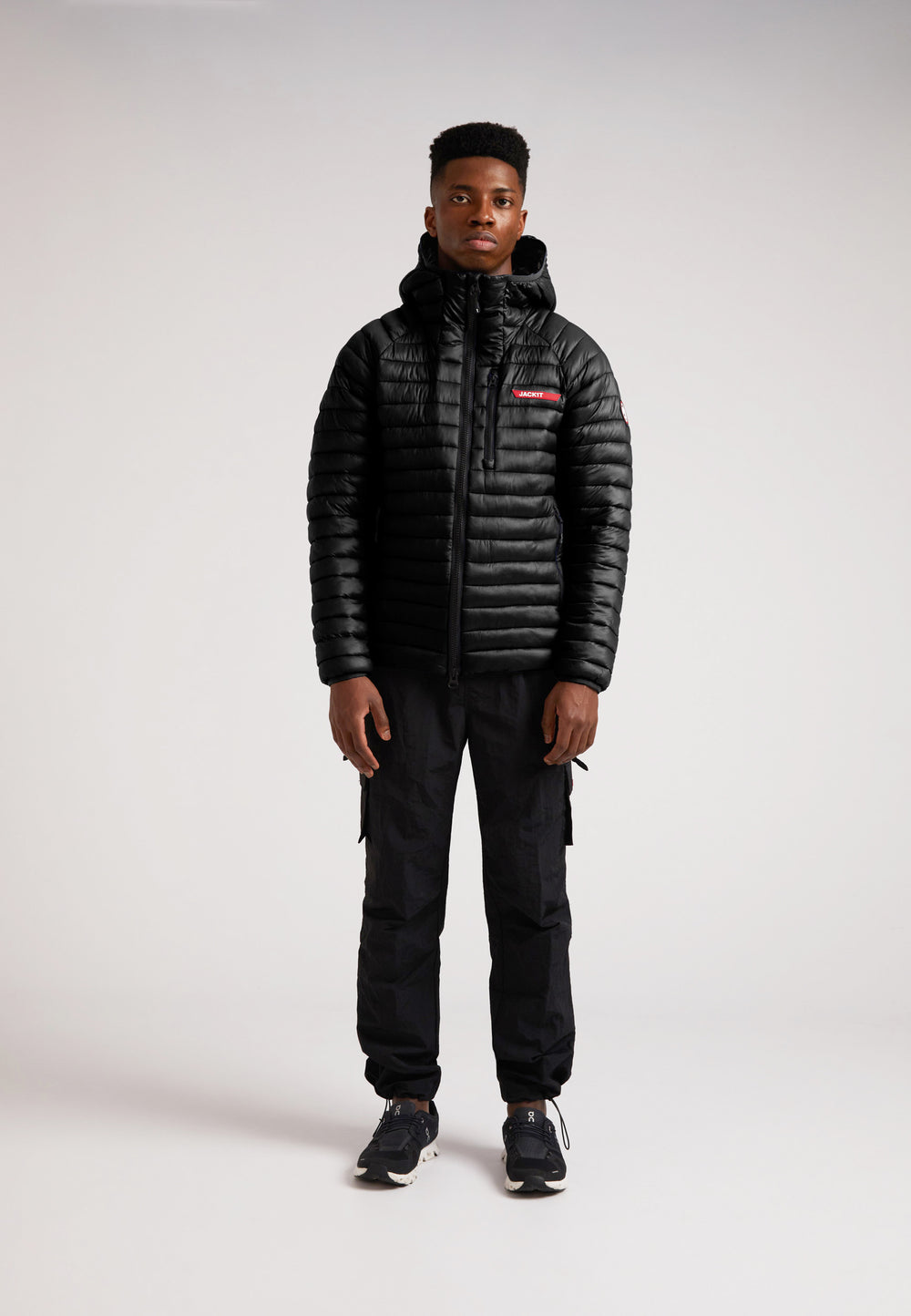 SATEL1TE Hooded Jacket 2.0 Black worn by a model, featuring a sleek design and PrimaLoft fill for comfort and style.