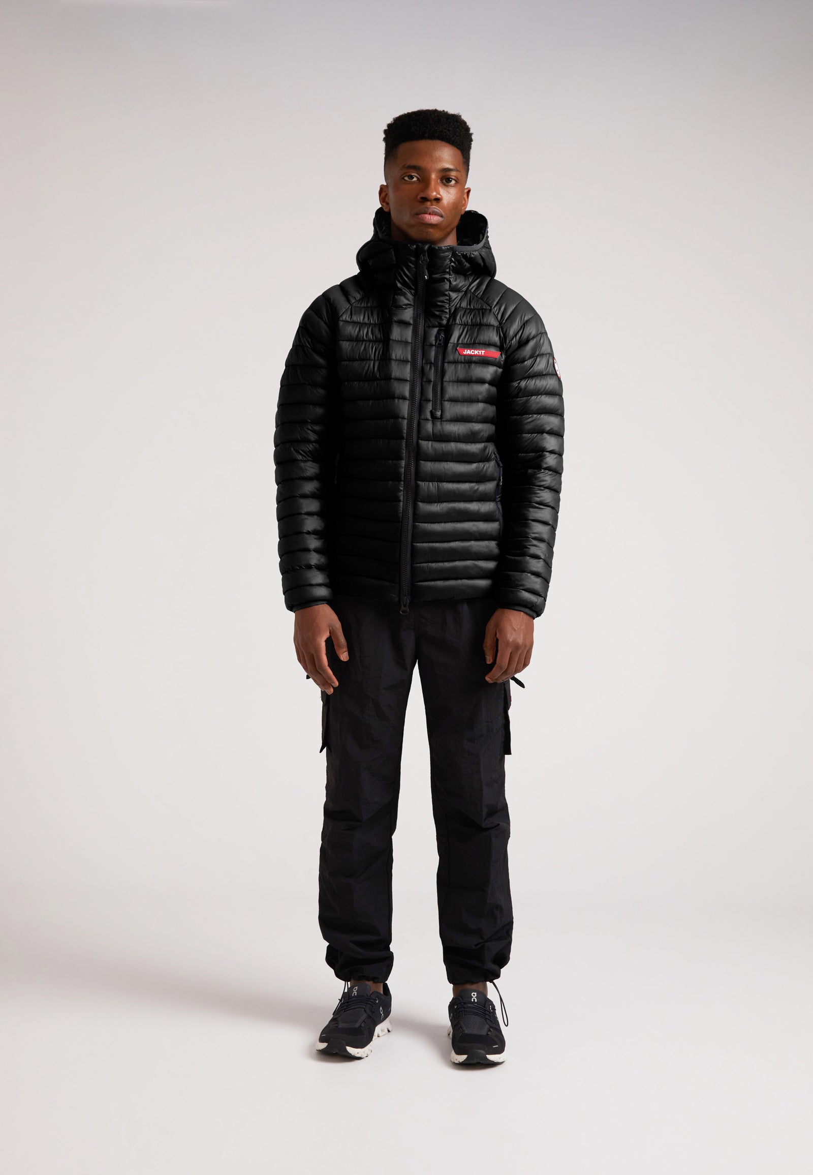 SATEL1TE Hooded Jacket 2.0 Black worn by a model, featuring a sleek design and PrimaLoft fill for comfort and style.