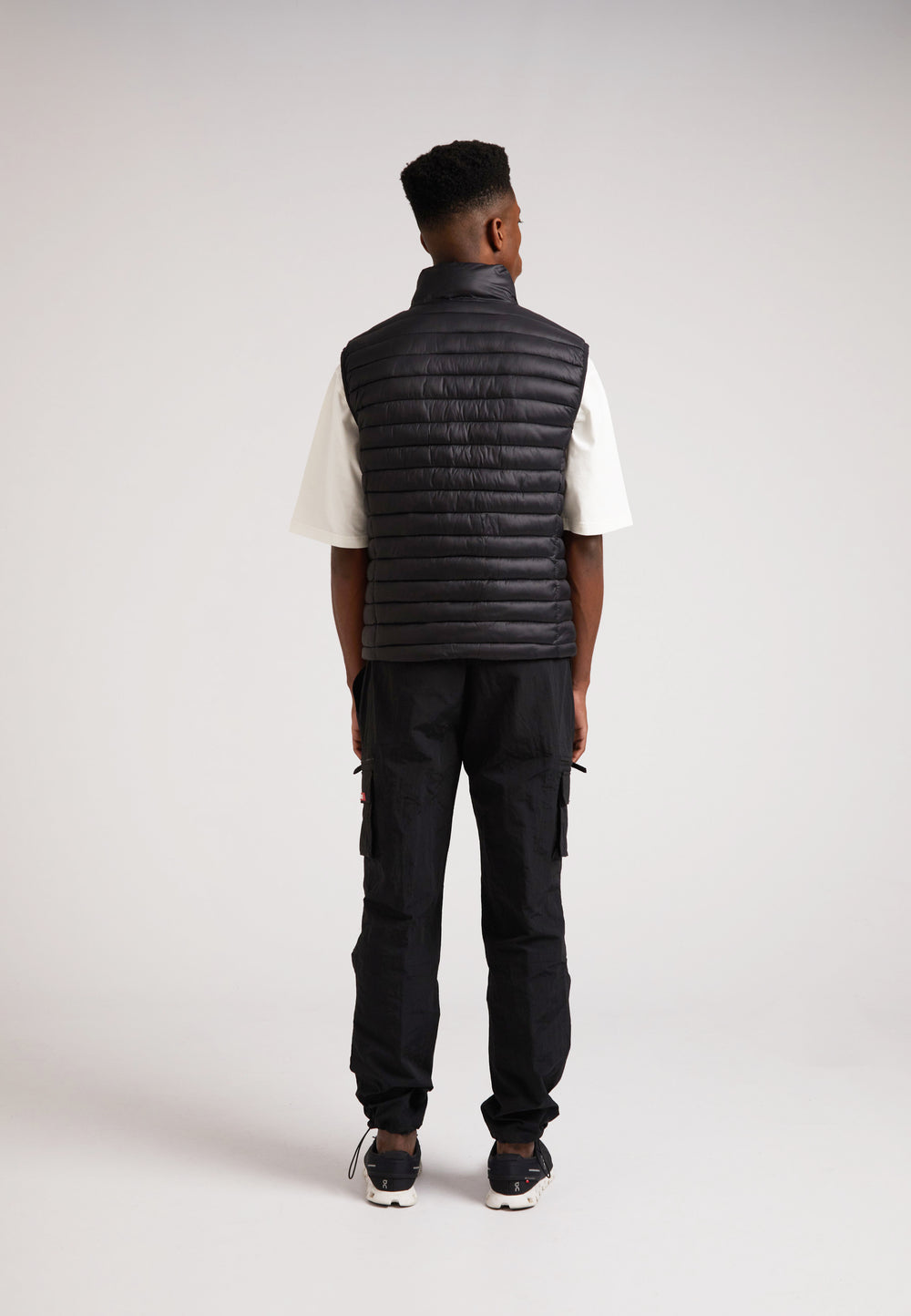 Man wearing SATEL1TE Lightweight Puffer Gilet 2.0 Black from the back, showcasing its sleek design and performance features.
