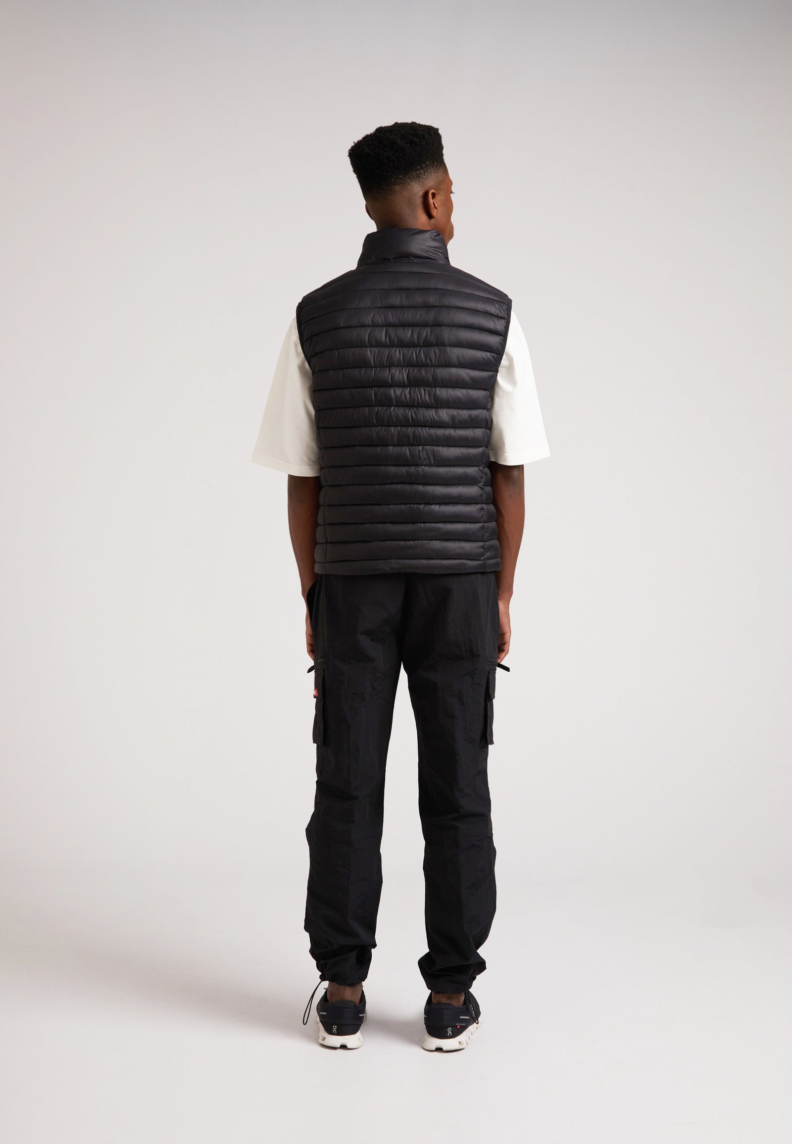 Man wearing SATEL1TE Lightweight Puffer Gilet 2.0 Black from the back, showcasing its sleek design and performance features.