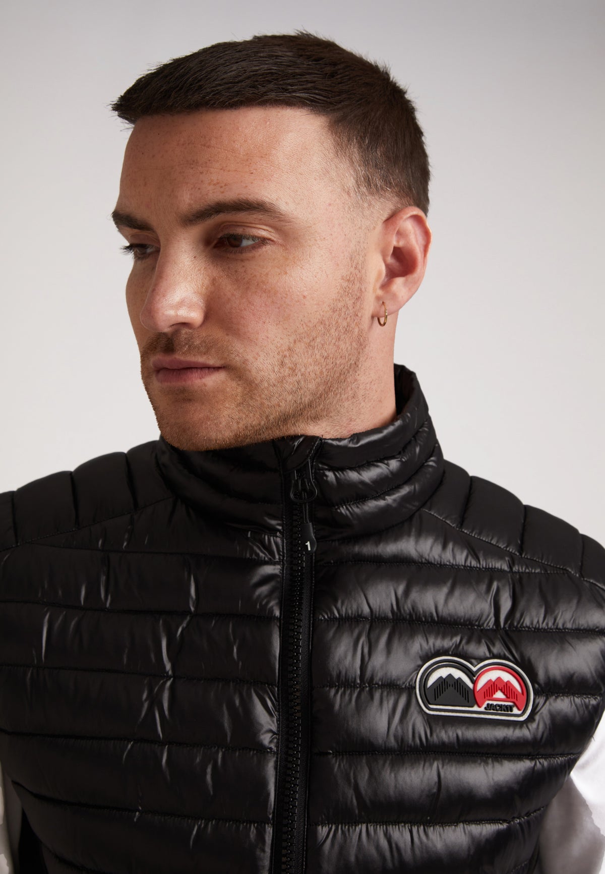 Close-up of a man wearing a black SPORTL1TE lightweight gilet for outdoor activities with a subtle logo.