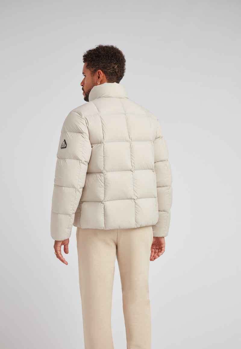 Back view of a man wearing the Cloud Lightweight Puffer Racer Jacket Stone in a light color.