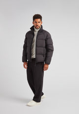Man wearing Cloud Lightweight Puffer Racer Jacket Black with stylish gray turtleneck and black trousers.