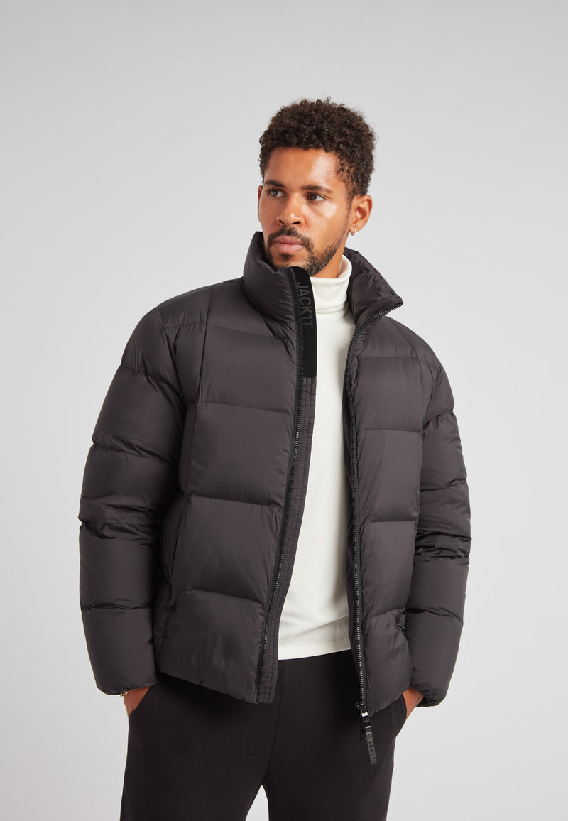 Model wearing Cloud Lightweight Puffer Racer Jacket Black, showcasing warmth and style for active winter wear.