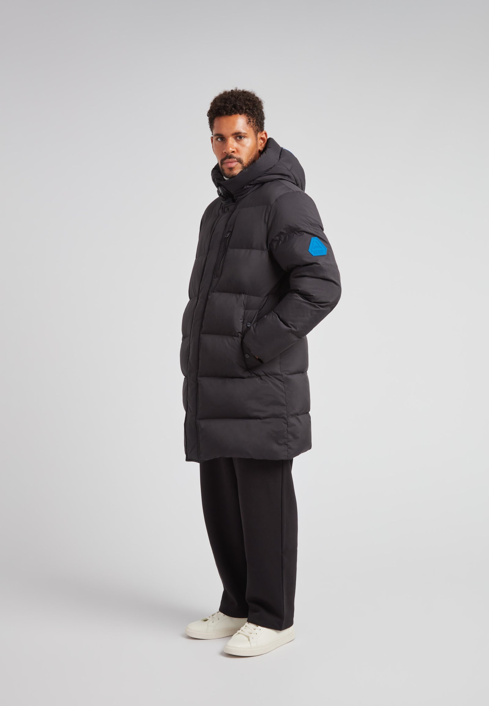Man wearing the Nomad Parka Coat 2.0 Black, a Down Parka Coat for Men in Black, providing warmth and style.