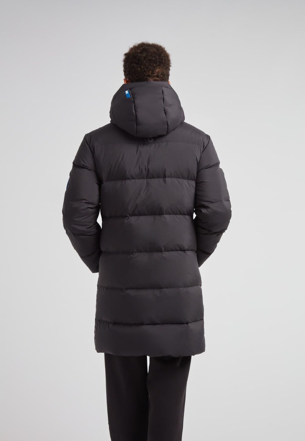 Back view of a man wearing a Down Parka Coat for Men in Black, showcasing its long length and padded design.