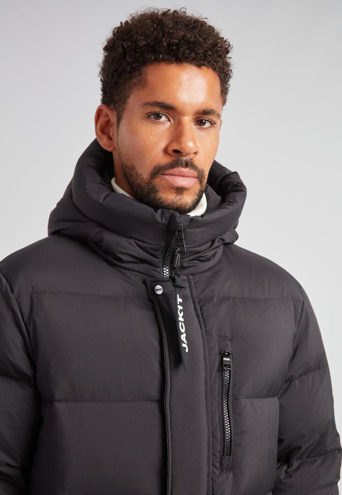 Down Parka Coat for Men in Black worn by a man, featuring a puffer design and hood for winter warmth.