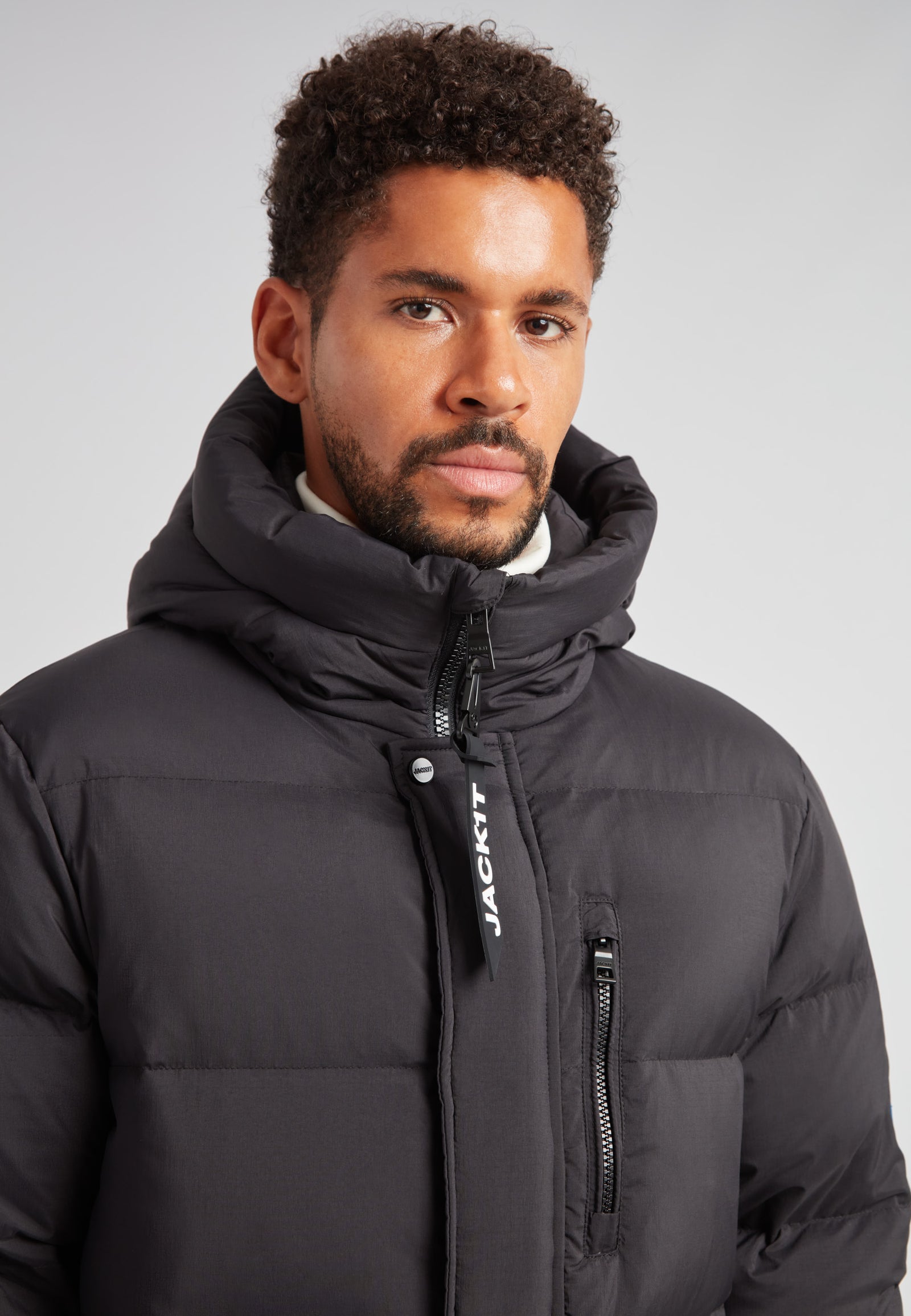 Down Parka Coat for Men in Black worn by a man, featuring a puffer design and hood for winter warmth.