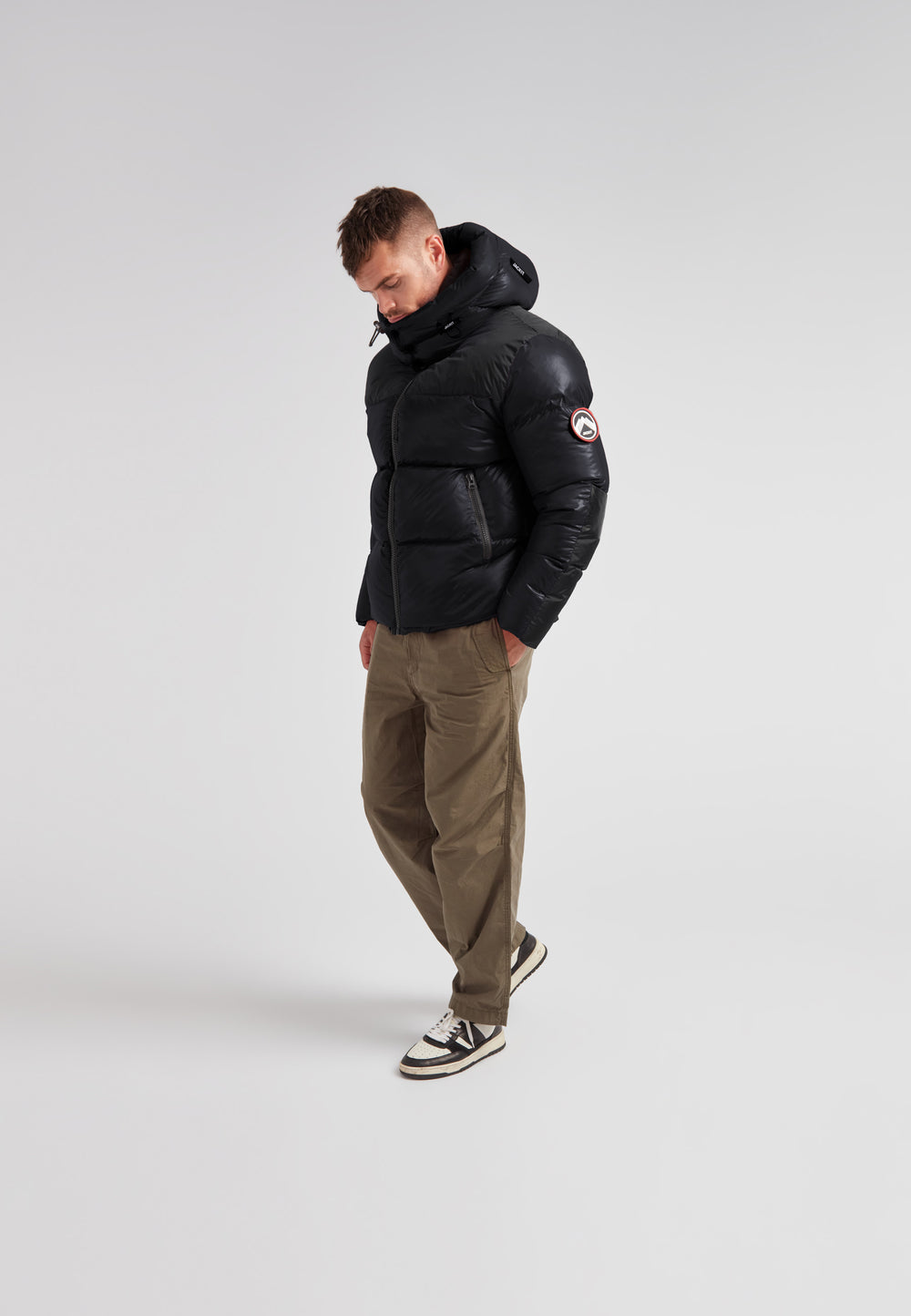 Man wearing Expedition Parka Puffer Men Black jacket with oversized hood and boxy silhouette.