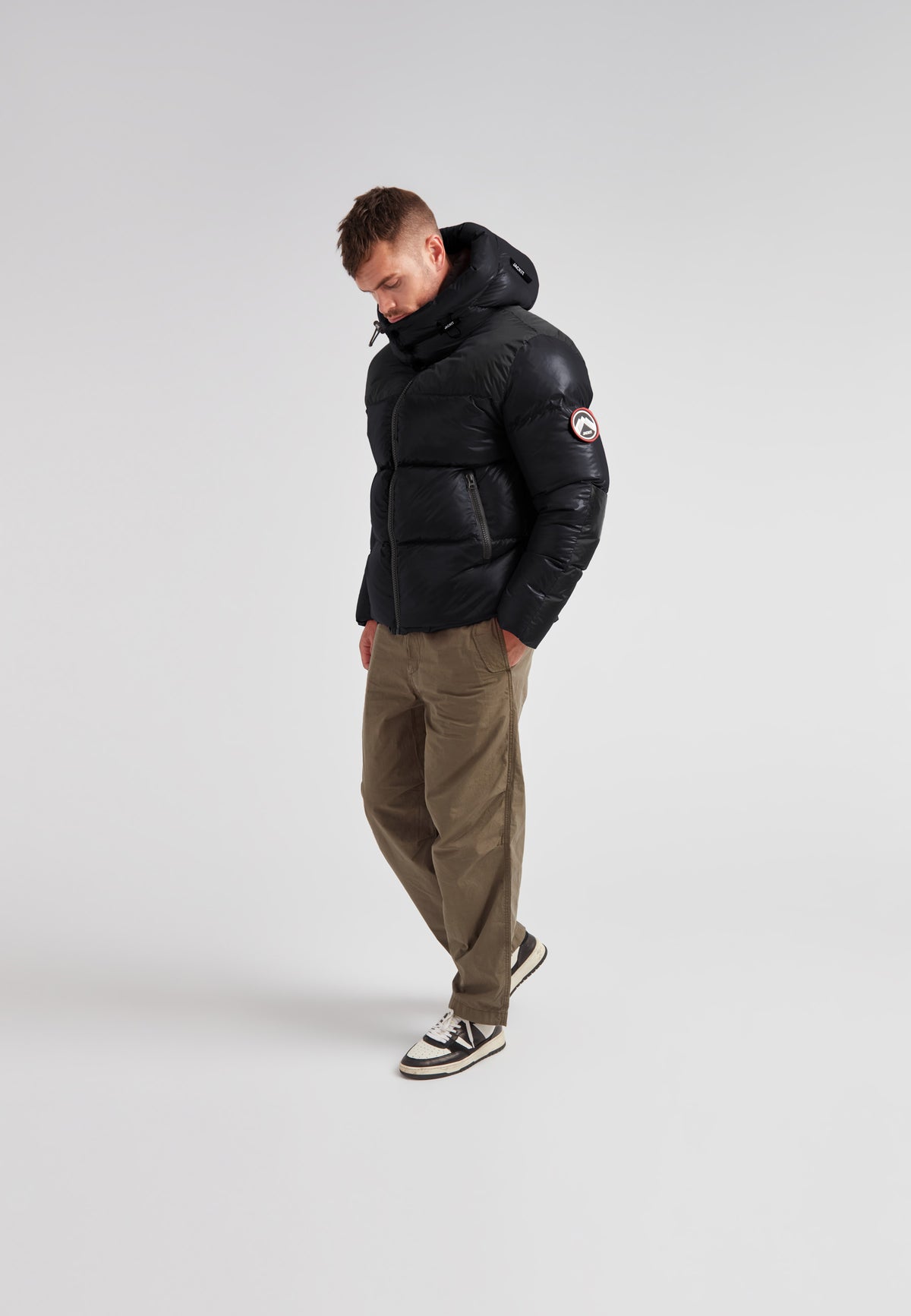Man wearing Expedition Parka Puffer Men Black jacket with oversized hood and boxy silhouette.