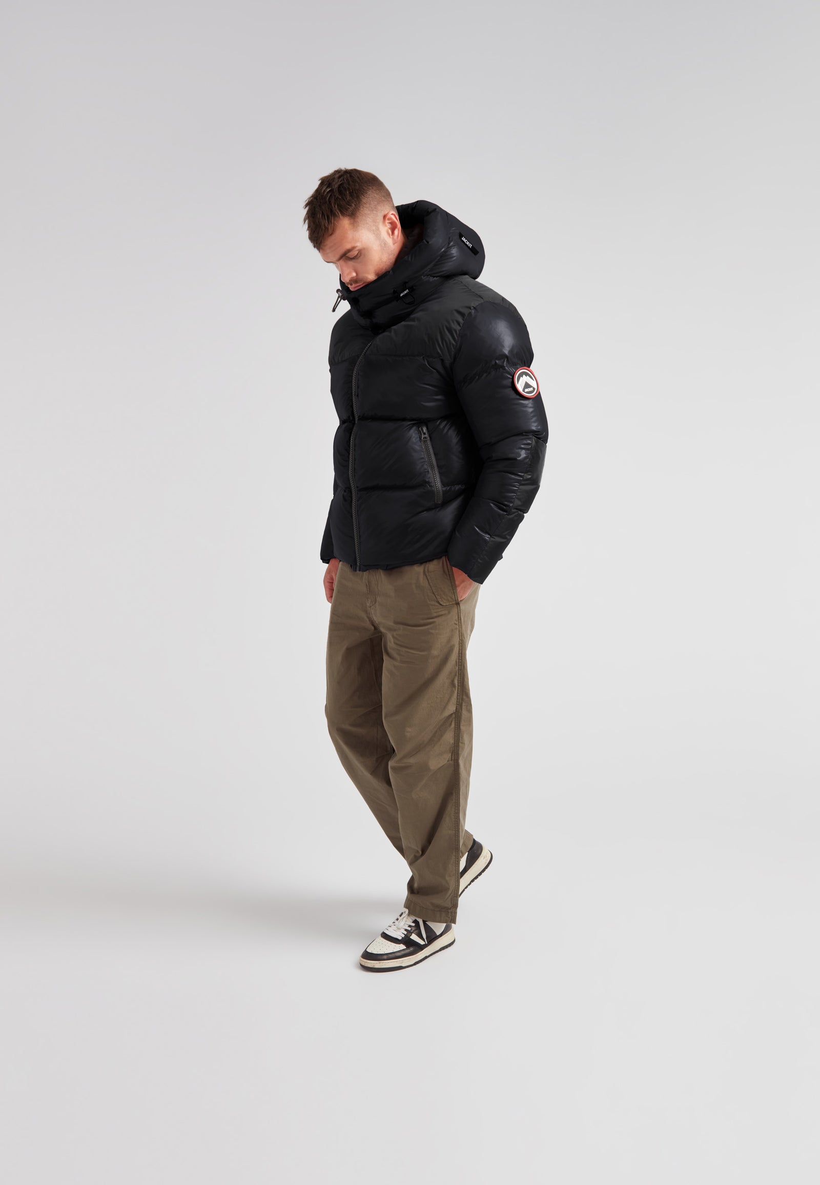 Man wearing Expedition Parka Puffer Men Black jacket with oversized hood and boxy silhouette.