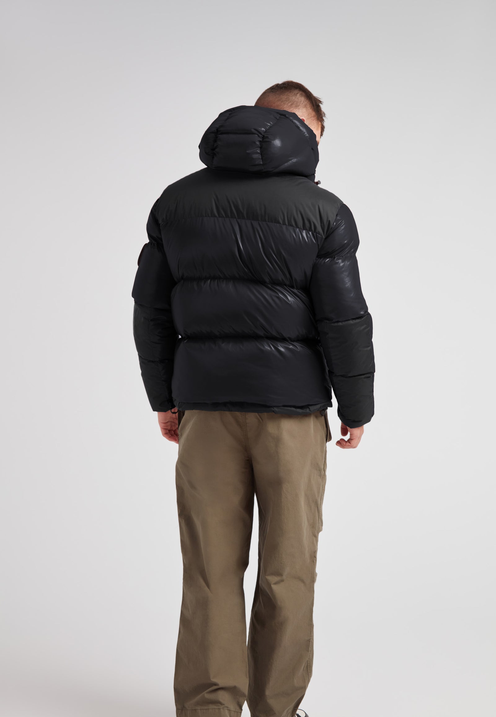 Back view of a man wearing an Expedition Parka Puffer Men Black jacket, showcasing its stylish, oversized hood and puffer design.