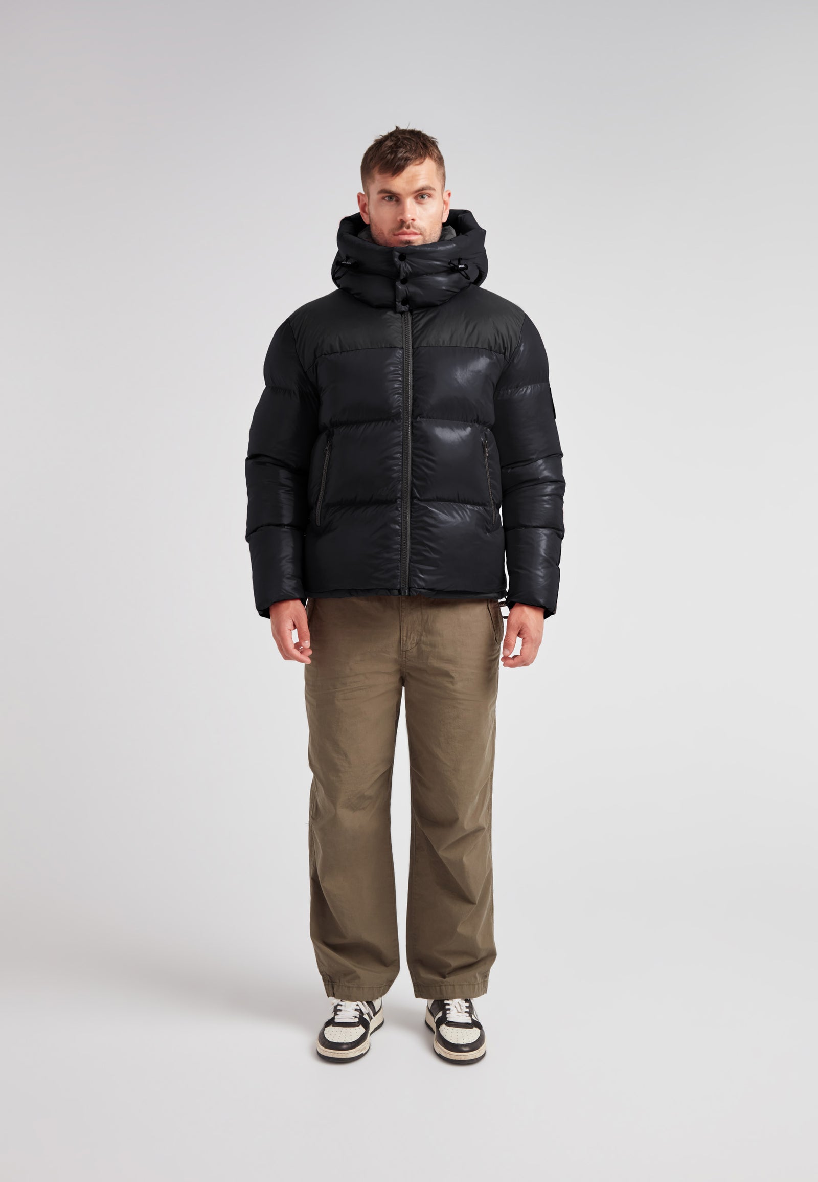 Man wearing the Expedition Parka Puffer Men Black jacket, featuring a boxy silhouette and oversized hood.