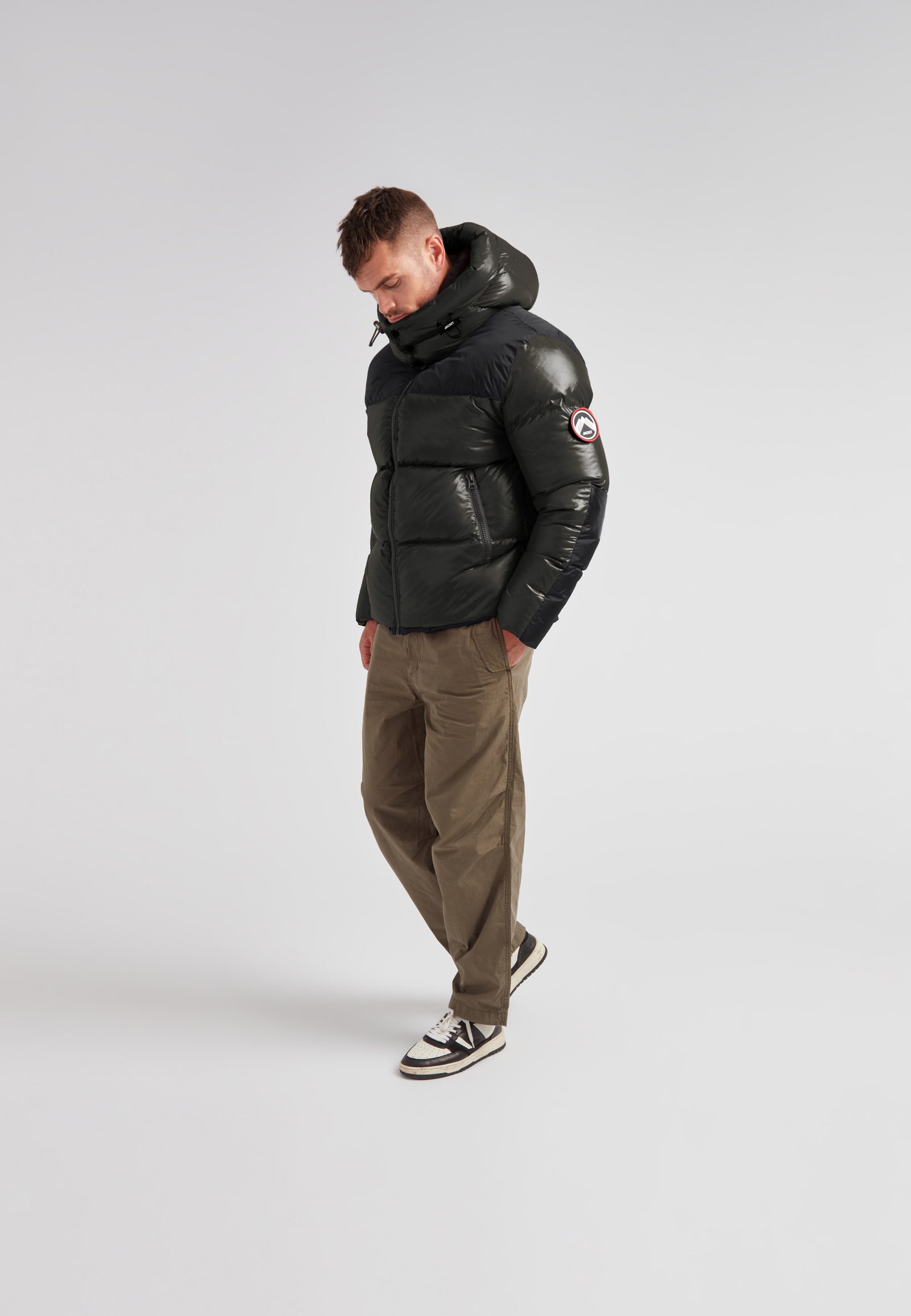 Man wearing Expedition Parka Puffer Men Emerald jacket with oversized hood and boxy silhouette.