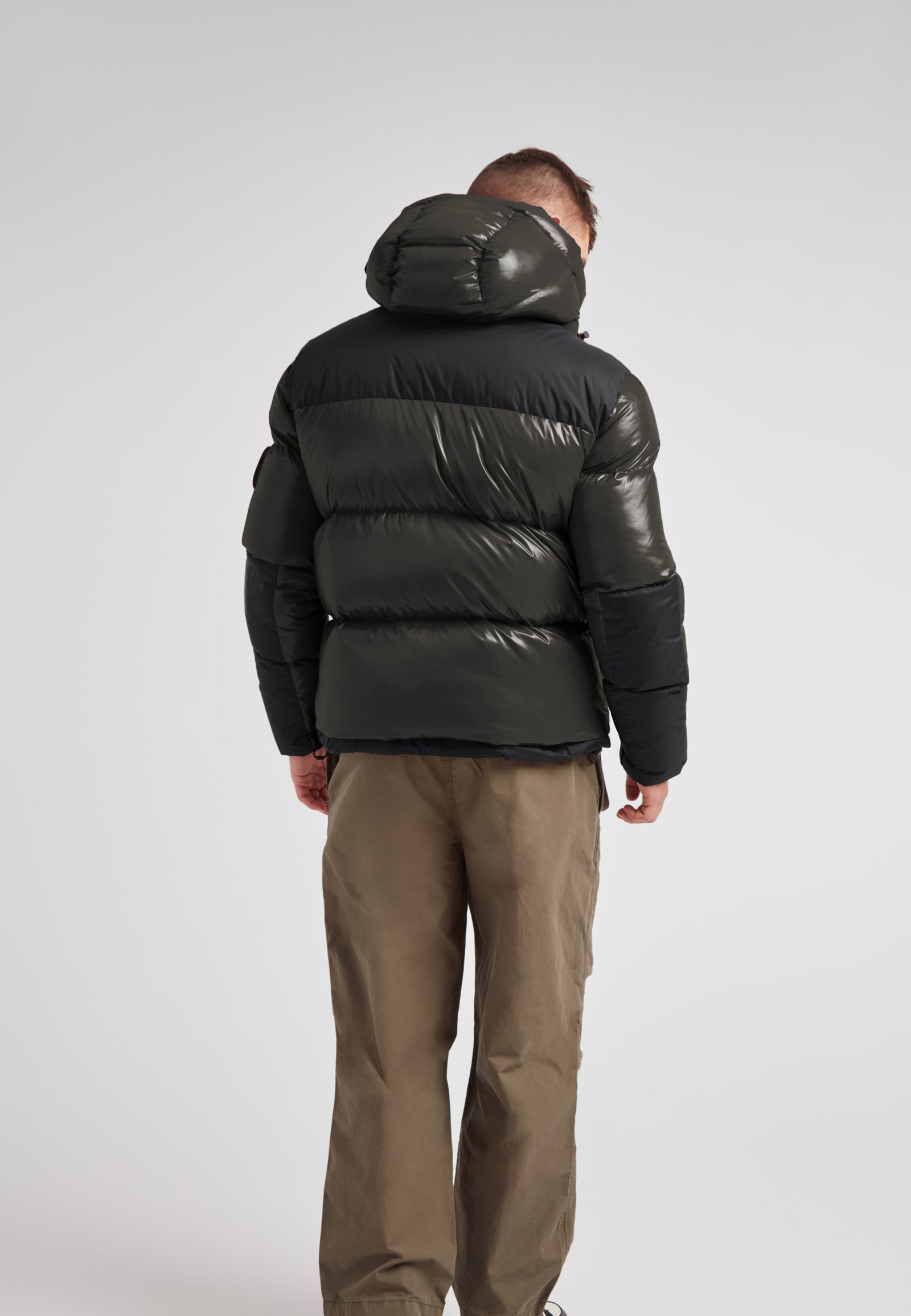 Back view of a man wearing the Expedition Parka Puffer Men Emerald jacket showcasing its bold color block design.