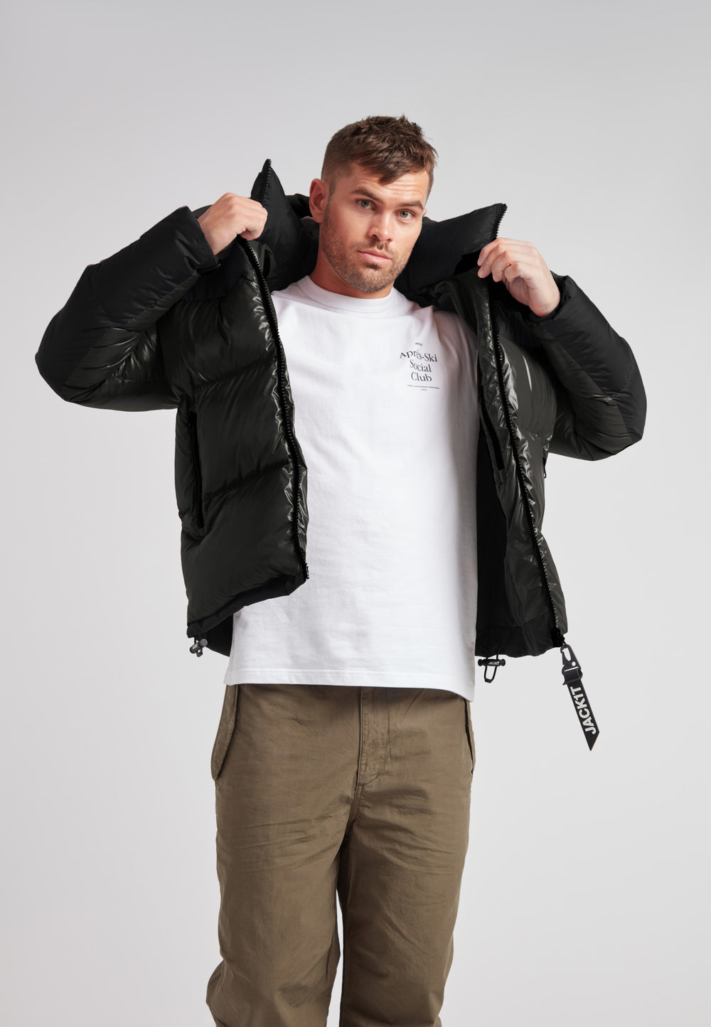 Man wearing Expedition Parka Puffer Men Emerald jacket adjusting the hood for warmth.