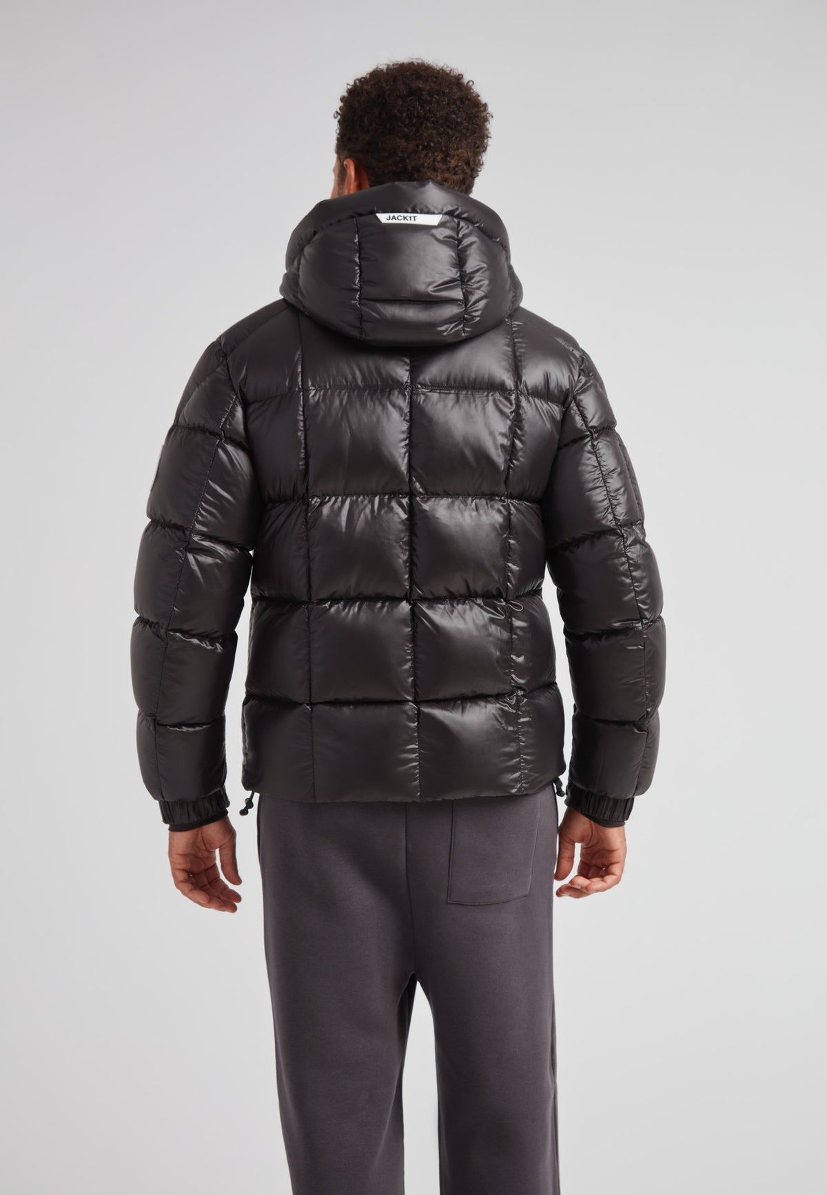 Back view of a man wearing the EZ Boxed Puffer Racer Jacket Lux Black, featuring a sleek quilted design and hood.