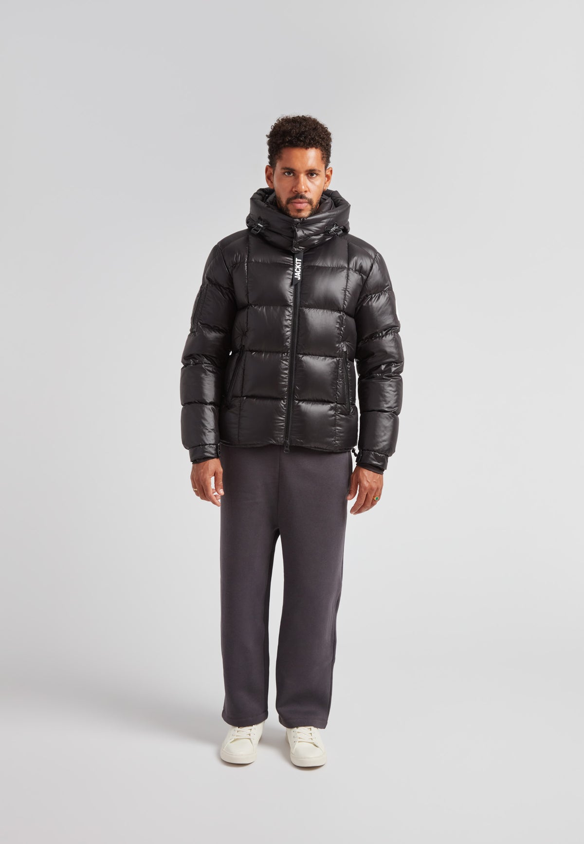 Model wearing EZ Boxed Puffer Racer Jacket Lux Black in asetting, showcasing its sleek design and warm features.