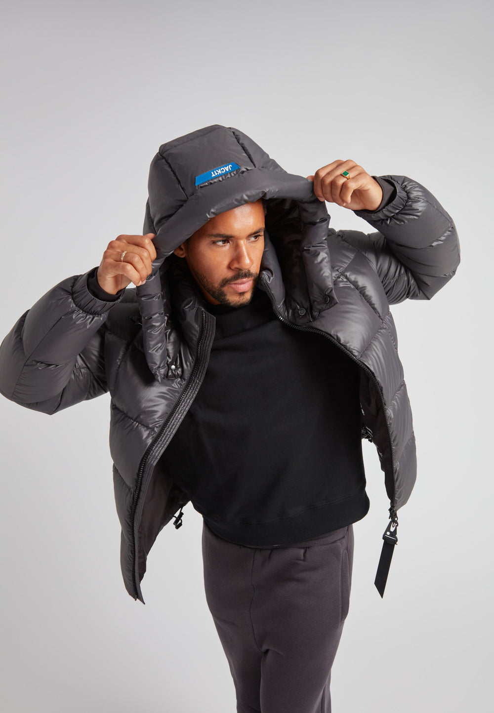 Man wearing the EZ Boxed Puffer Racer Jacket Lux Graphite with the hood up, showcasing its sleek design and winter-ready features.