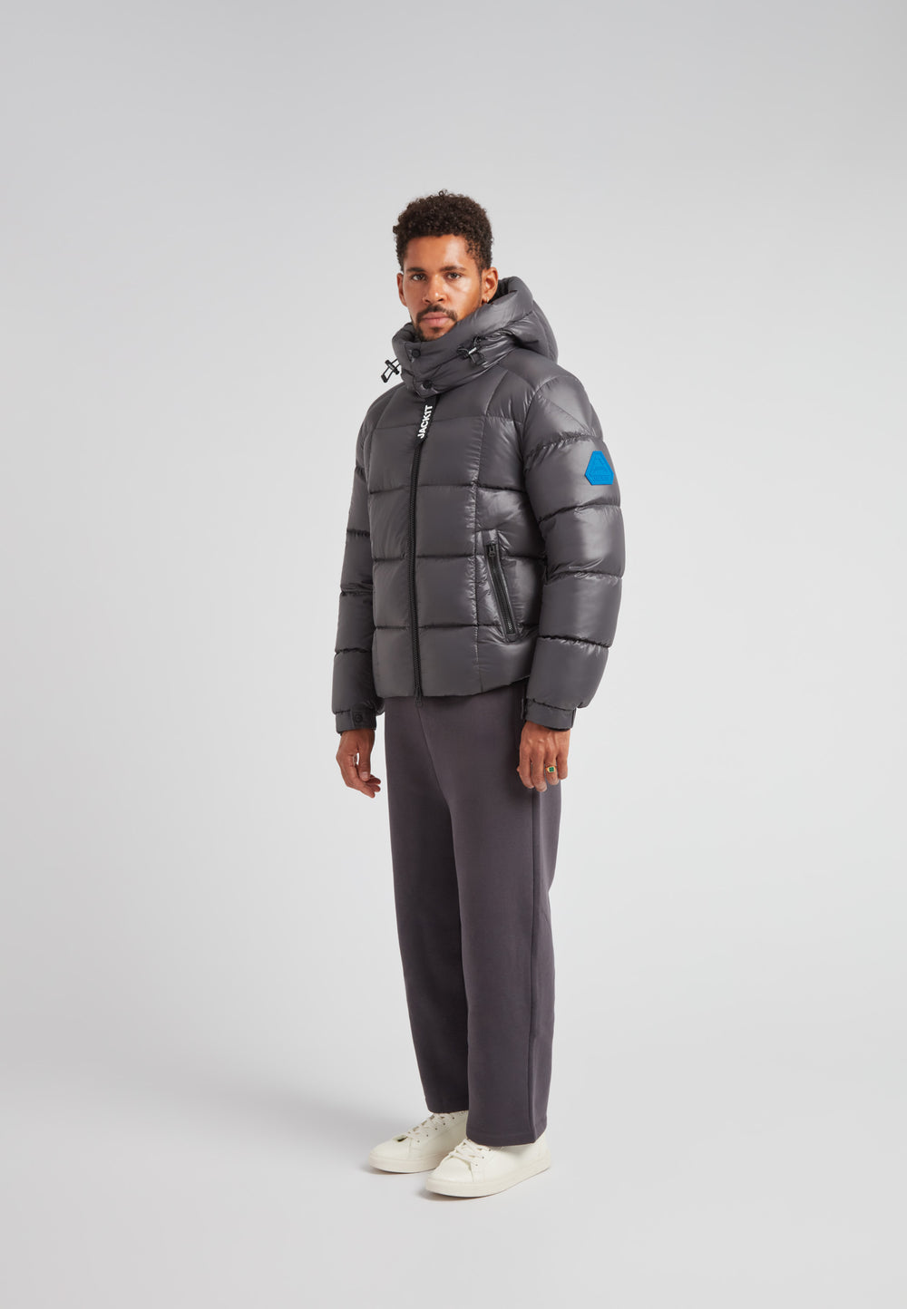 Model wearing EZ Boxed Puffer Racer Jacket Lux Graphite with hood and puffer design in a studio setting.