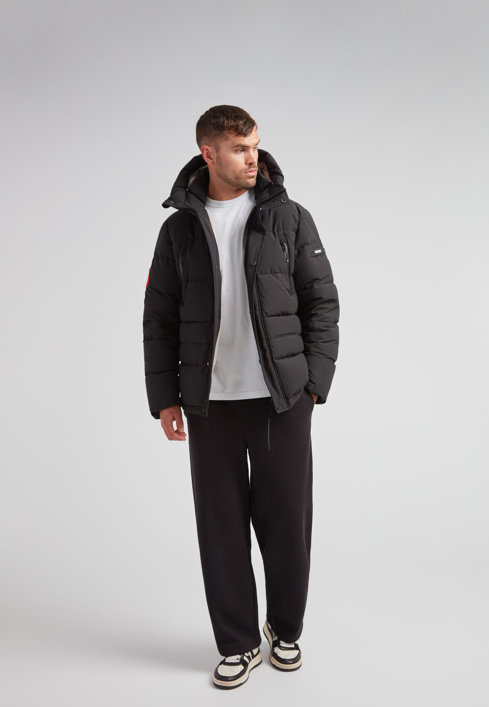 Man wearing EZ Frontier Prime Down Puffer Jacket Matt Black with casual style, showcasing urban winter fashion.