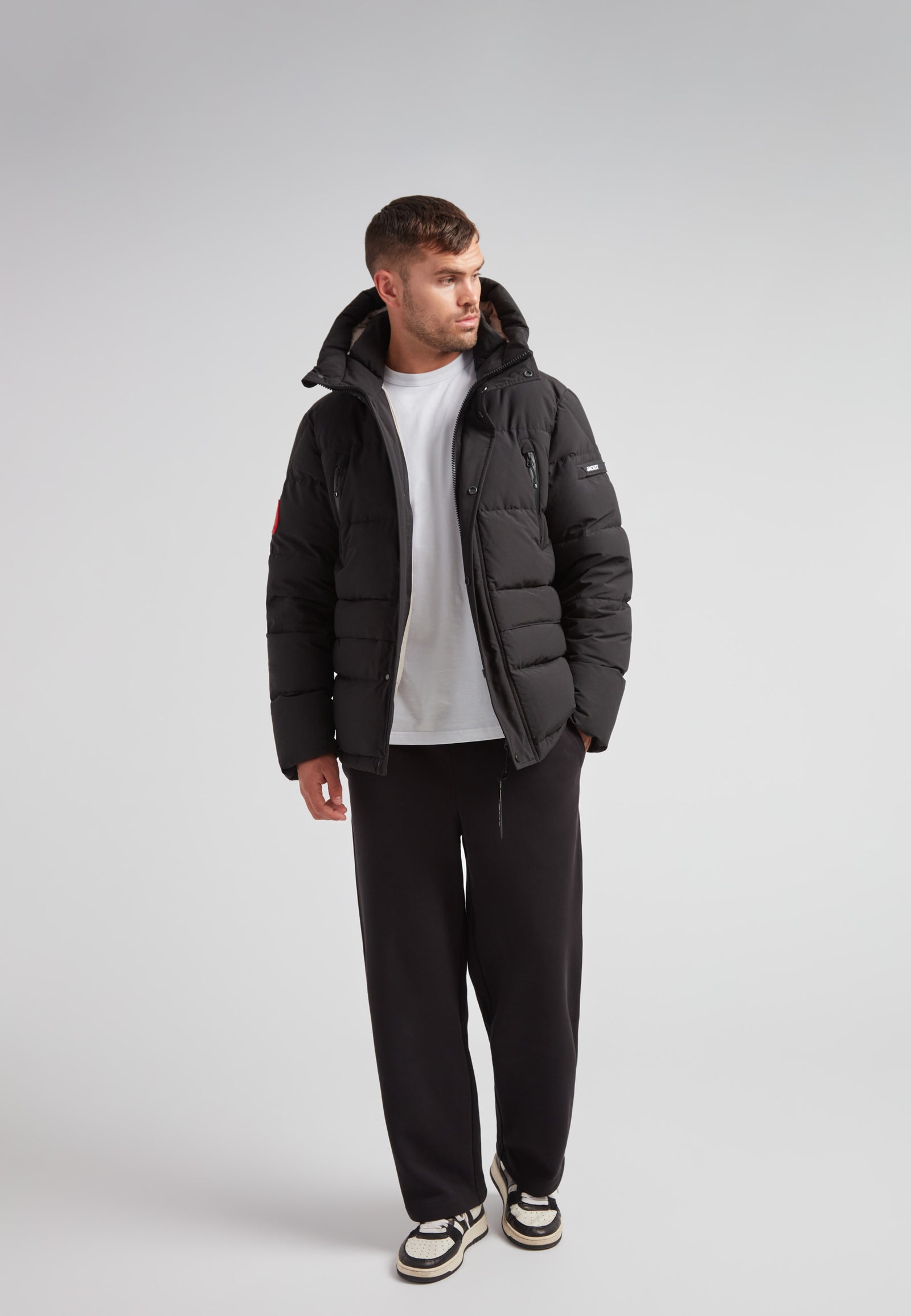 Man wearing EZ Frontier Prime Down Puffer Jacket Matt Black with casual style, showcasing urban winter fashion.