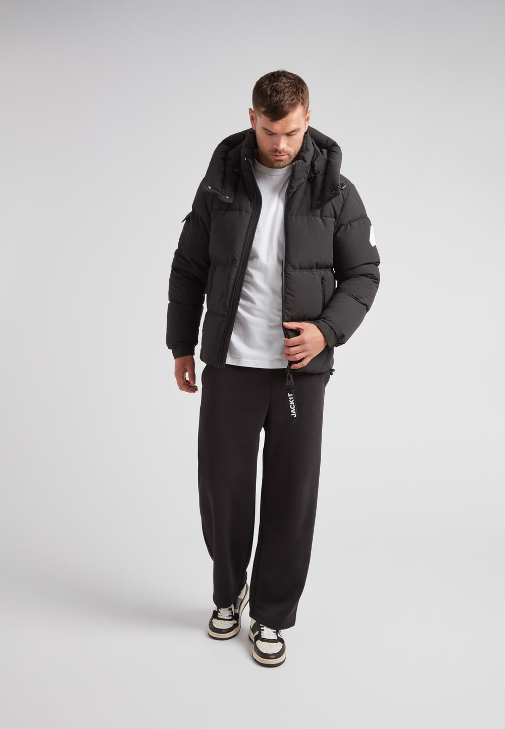 Model wearing EZ Water Puffer Racer Jacket Matt Black with casual outfit in studio setting.